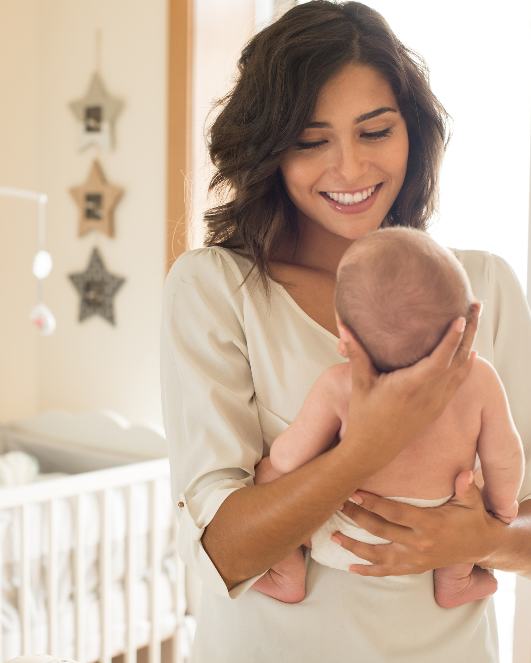 A woman holding a sleeping baby in a nursery with star-shaped decorations on the wall.