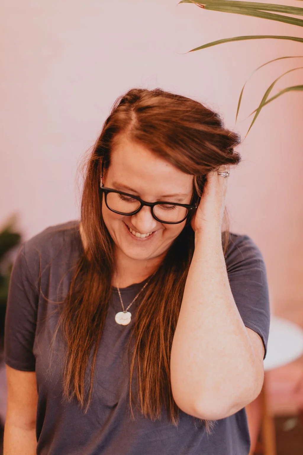 Carly Smith, Bold Vibes Marketing, is smiling and looking down with her hand in her hair.
