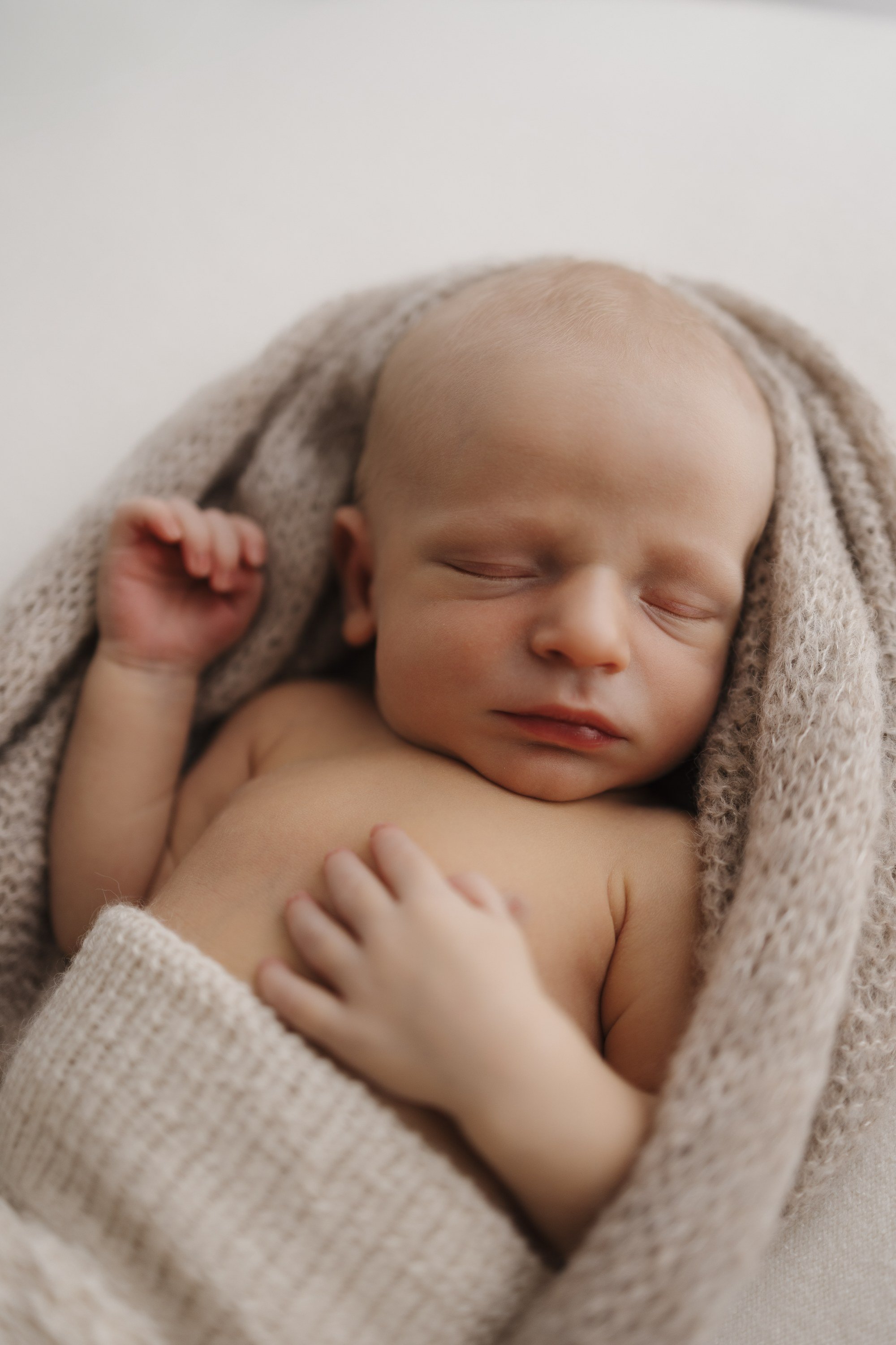 A peaceful sleeping baby wrapped in a cozy beige blanket.