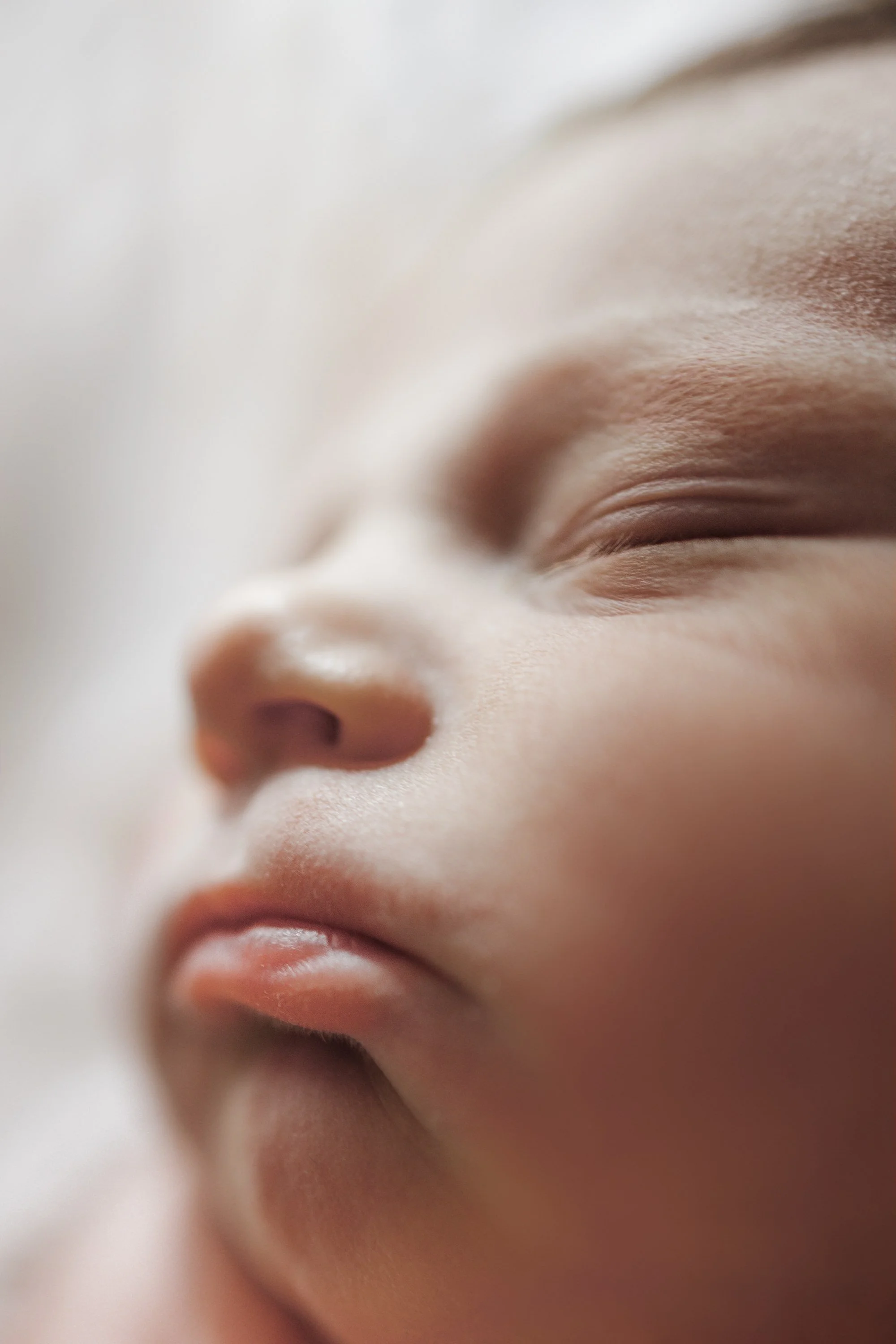 Close-up of a sleeping baby's face showing peaceful expression, closed eyes, small nose, and lips.