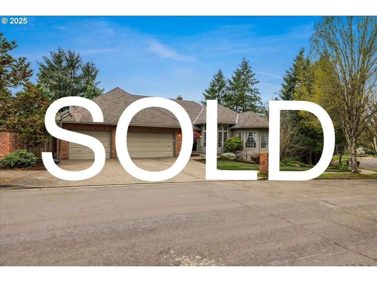 A house with a three-car garage, trees, and a clear blue sky, with the word SOLD overlaid in large white letters.