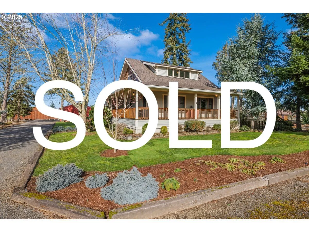 A house with a large front porch and a well-maintained garden, large trees, a driveway, and a bright blue sky. The word 'SOLD' is overlaid on the image.