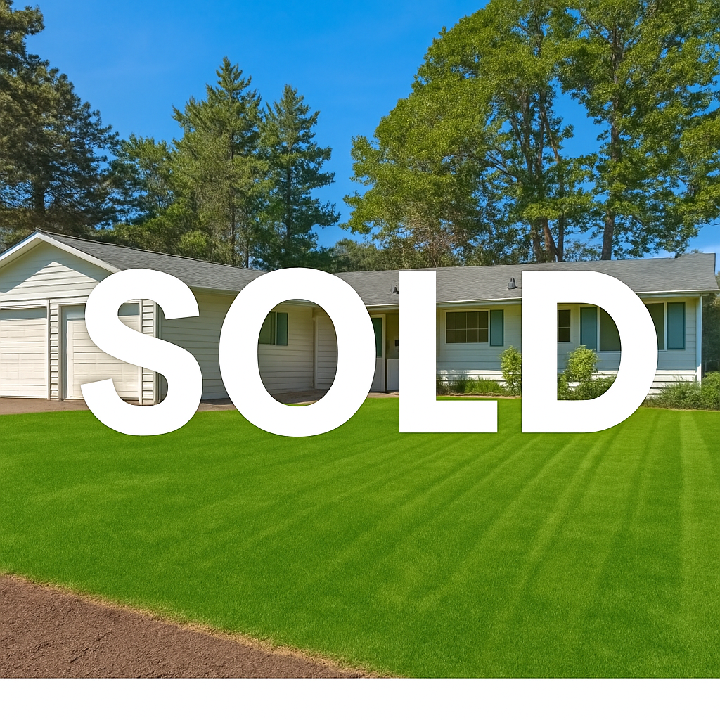 A white house with a gray roof, surrounded by green trees and a well-manicured lawn, with a blue sky overhead. The word "SOLD" in large white letters is overlayed across the image.