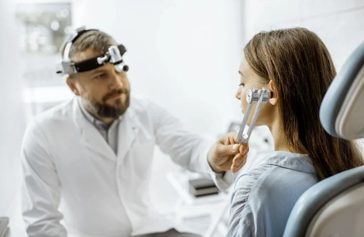 Dentist examining a woman's ear with a medical instrument in a dental office.