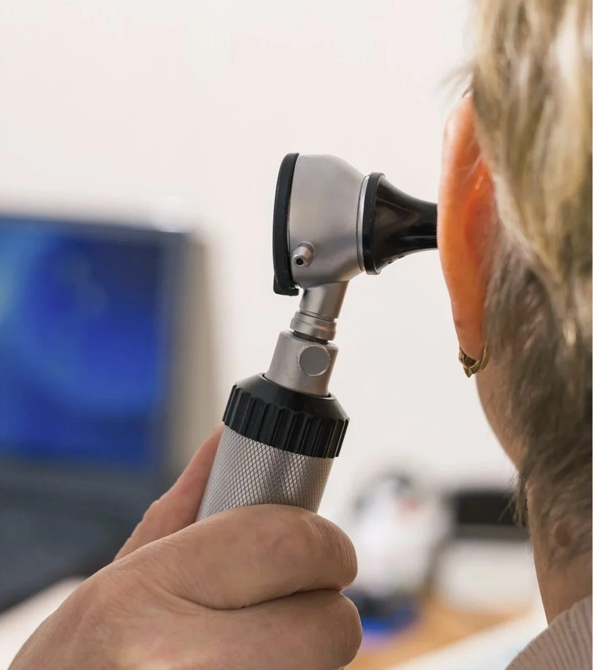 A person using an otoscope to examine a patient's ear.