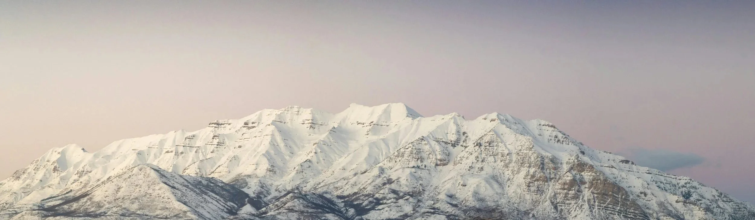 Snow-covered mountain range under a cloudy sky.