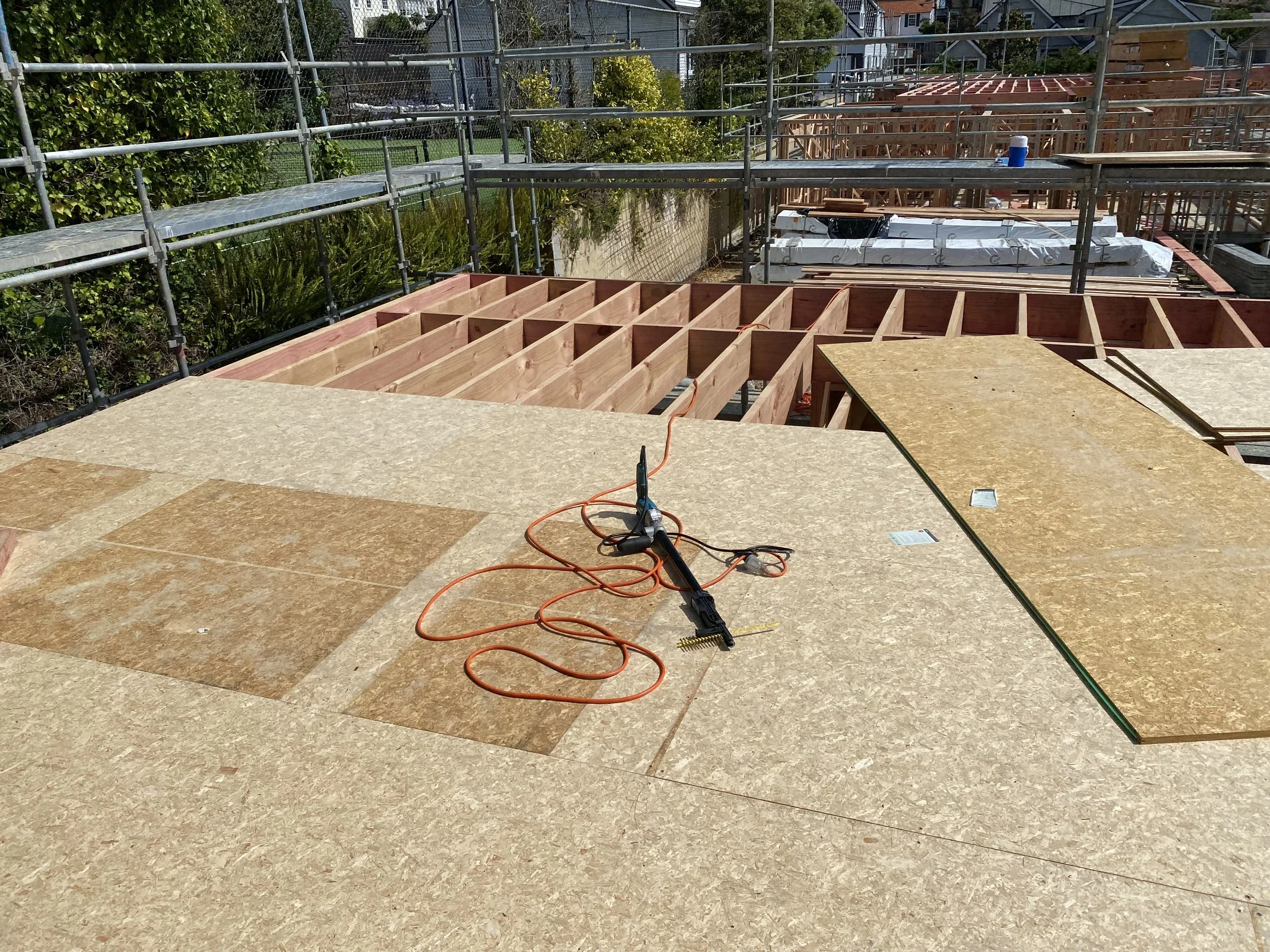 Construction site with plywood flooring, electrical tools, and wooden framing for a building.