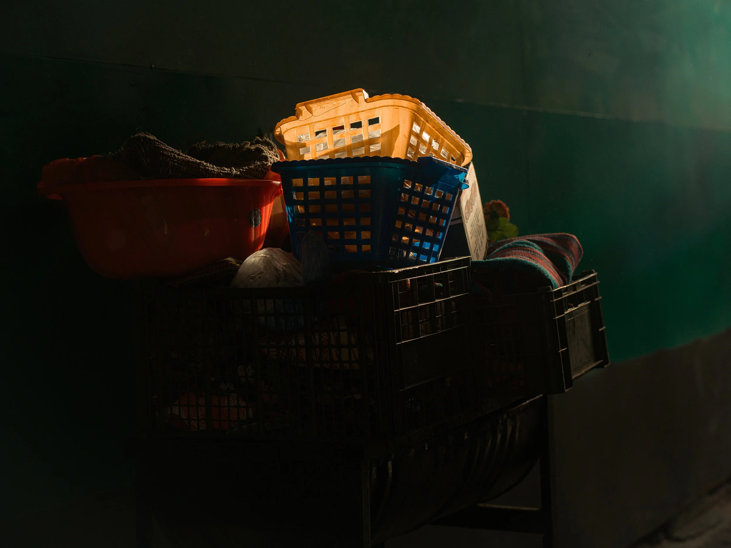 In Chichicastenango market. Guatemala, a collection of plastic baskets and crates with laundry and miscellaneous items, illuminated by a soft light.