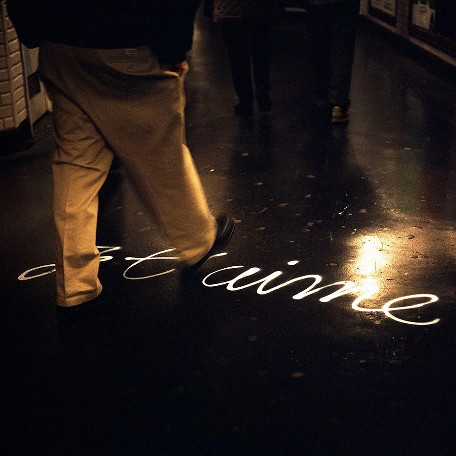 A person walking over a black floor with the words 'art is time' written in white cursive on the ground.