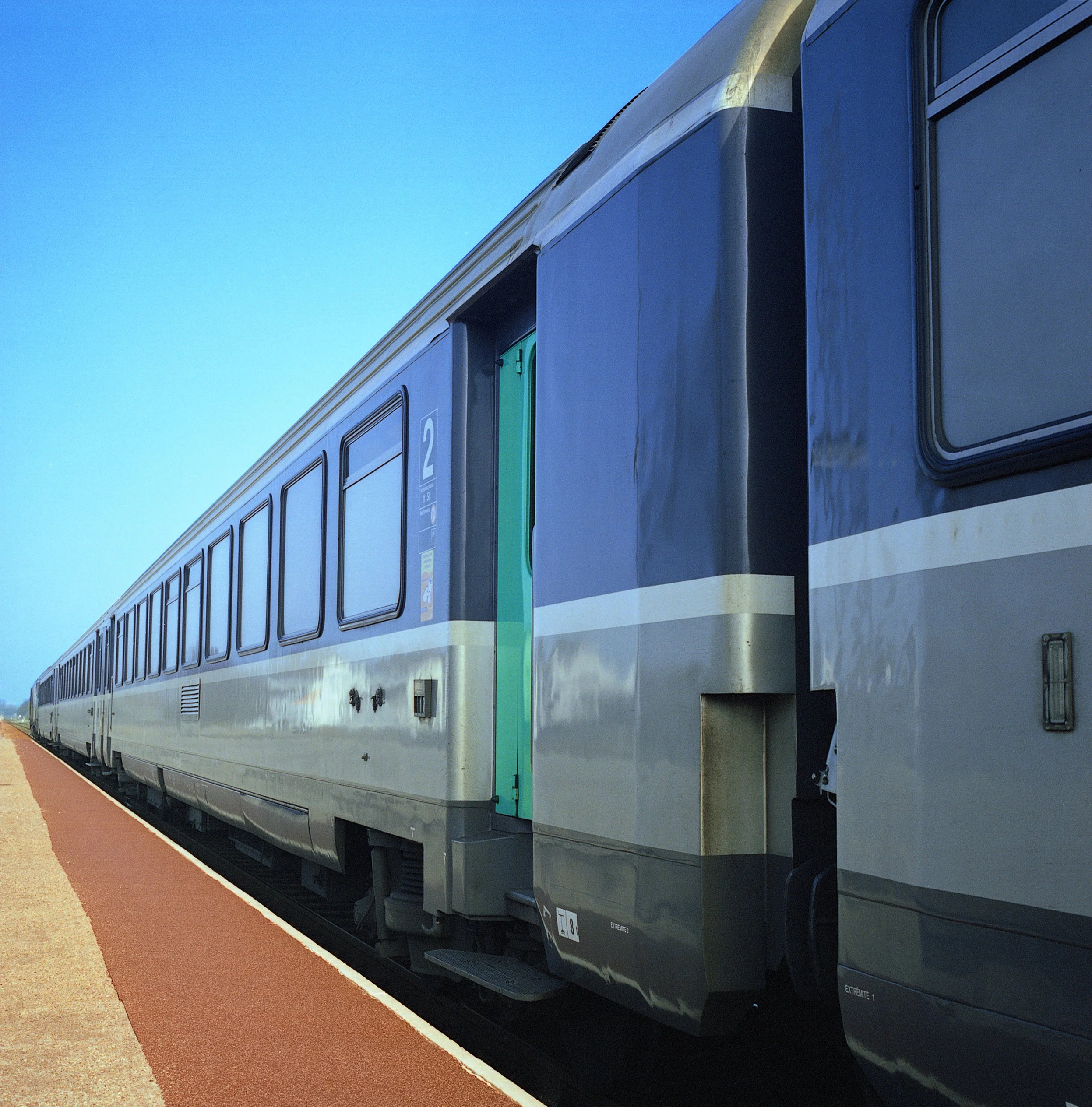 A train on a railway track under a clear blue sky.