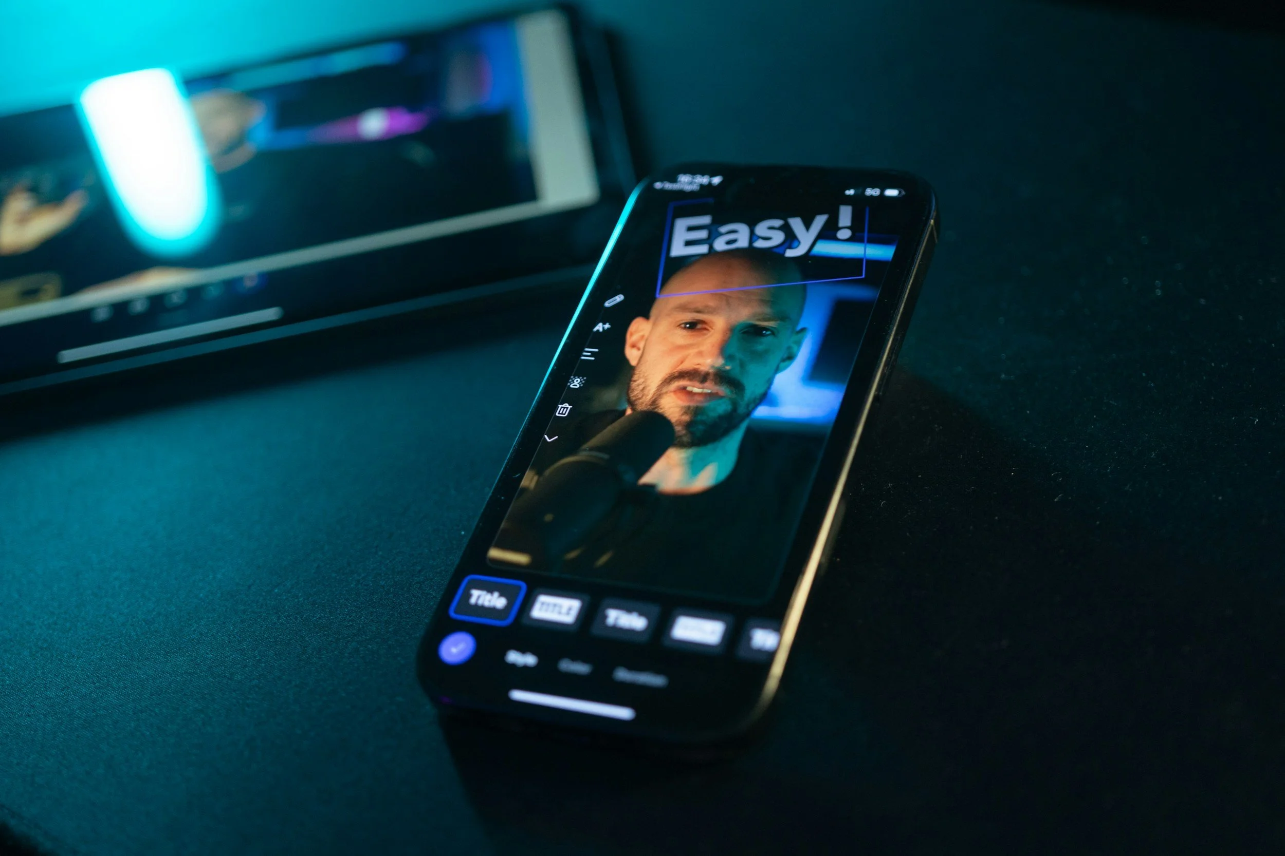 A smartphone lying on a dark surface displays a photo of a man's face with the word 'Easy!' at the top.