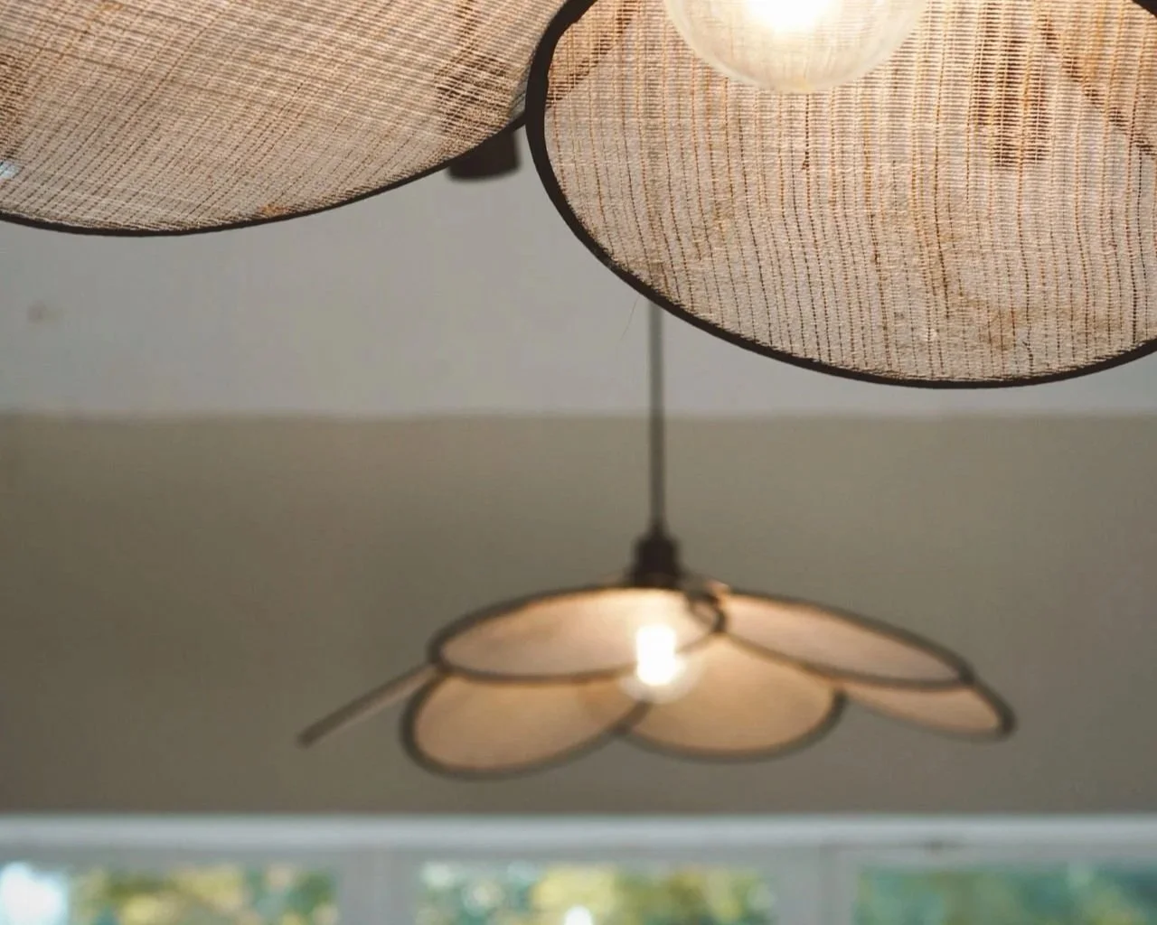Close-up of a ceiling lamp with three fabric lampshades and a flower-shaped light fixture hanging below.