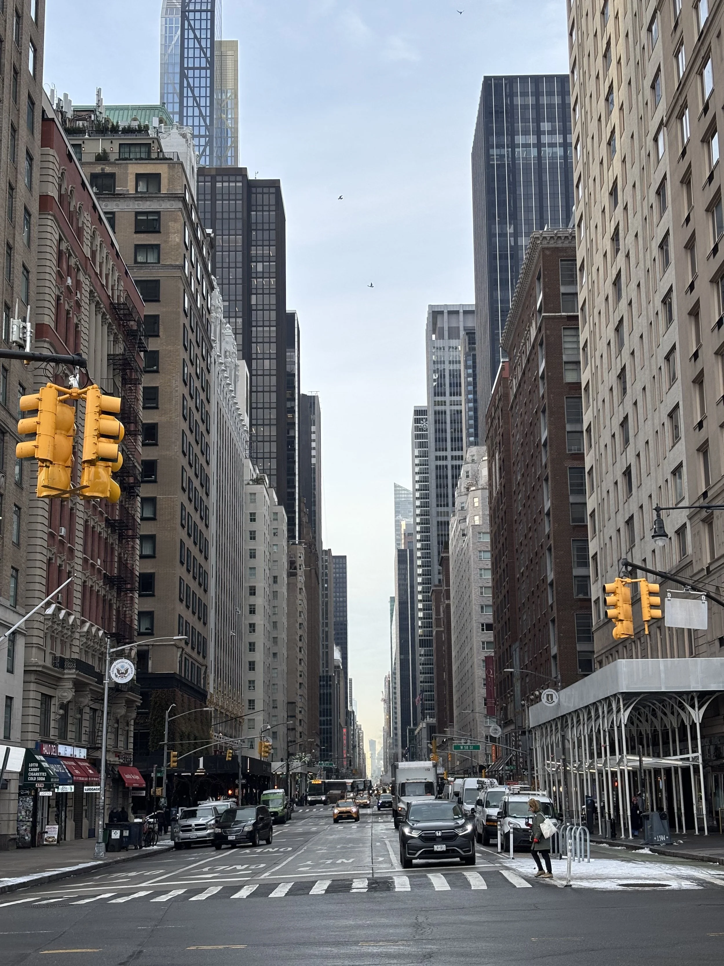 Straße in einer Stadt mit Hochhäusern, Autos und Fußgängern, vermutlich in New York City.