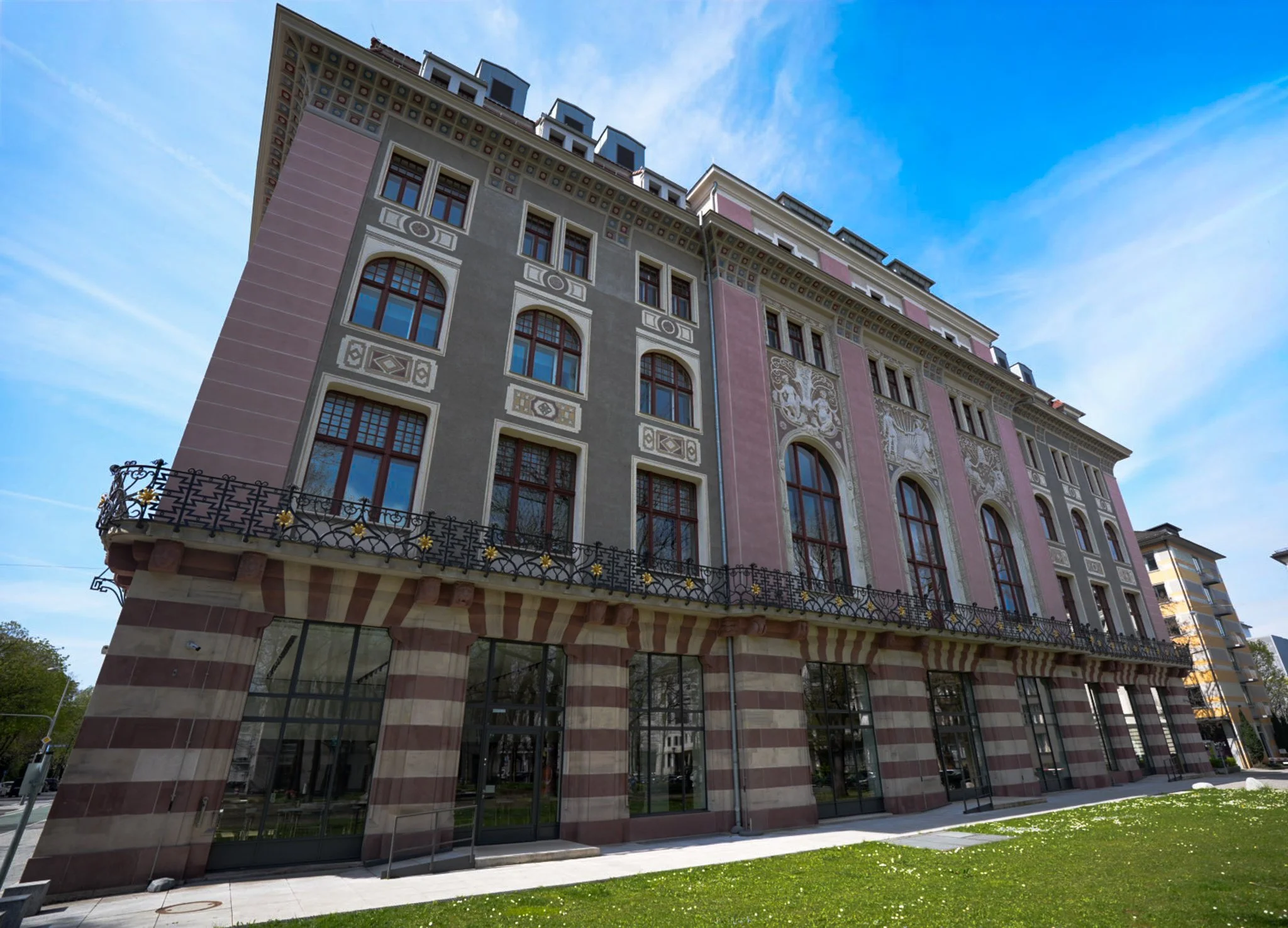 Hochhäuser mit historischen Fassaden, unter einem blauen Himmel, im Stadtzentrum, mit stilvollem Balkon und großen Fenstern.