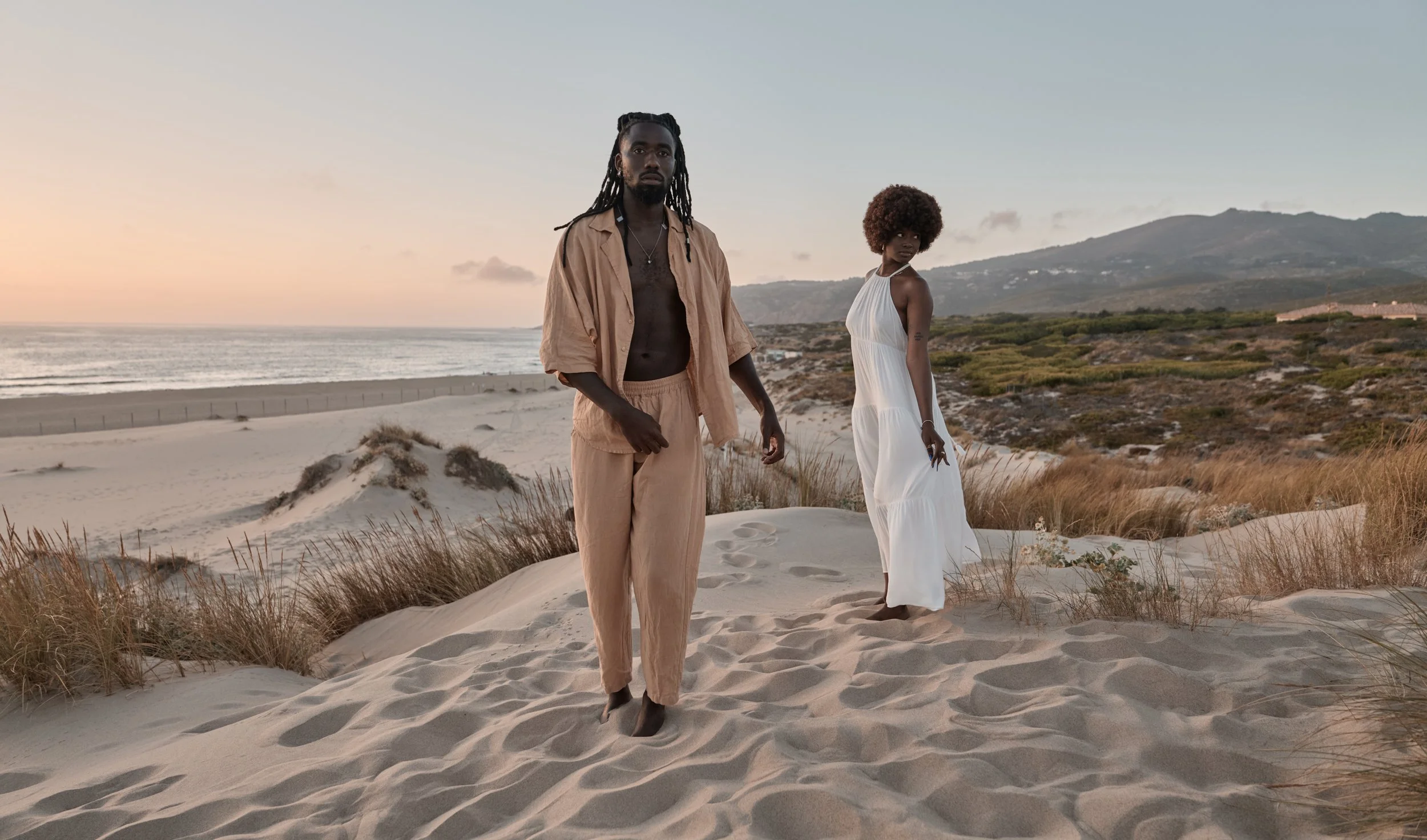 black-couple-standing-away-on-sand-with-dry-grass-2026-01-09-06-45-37-utc.jpg