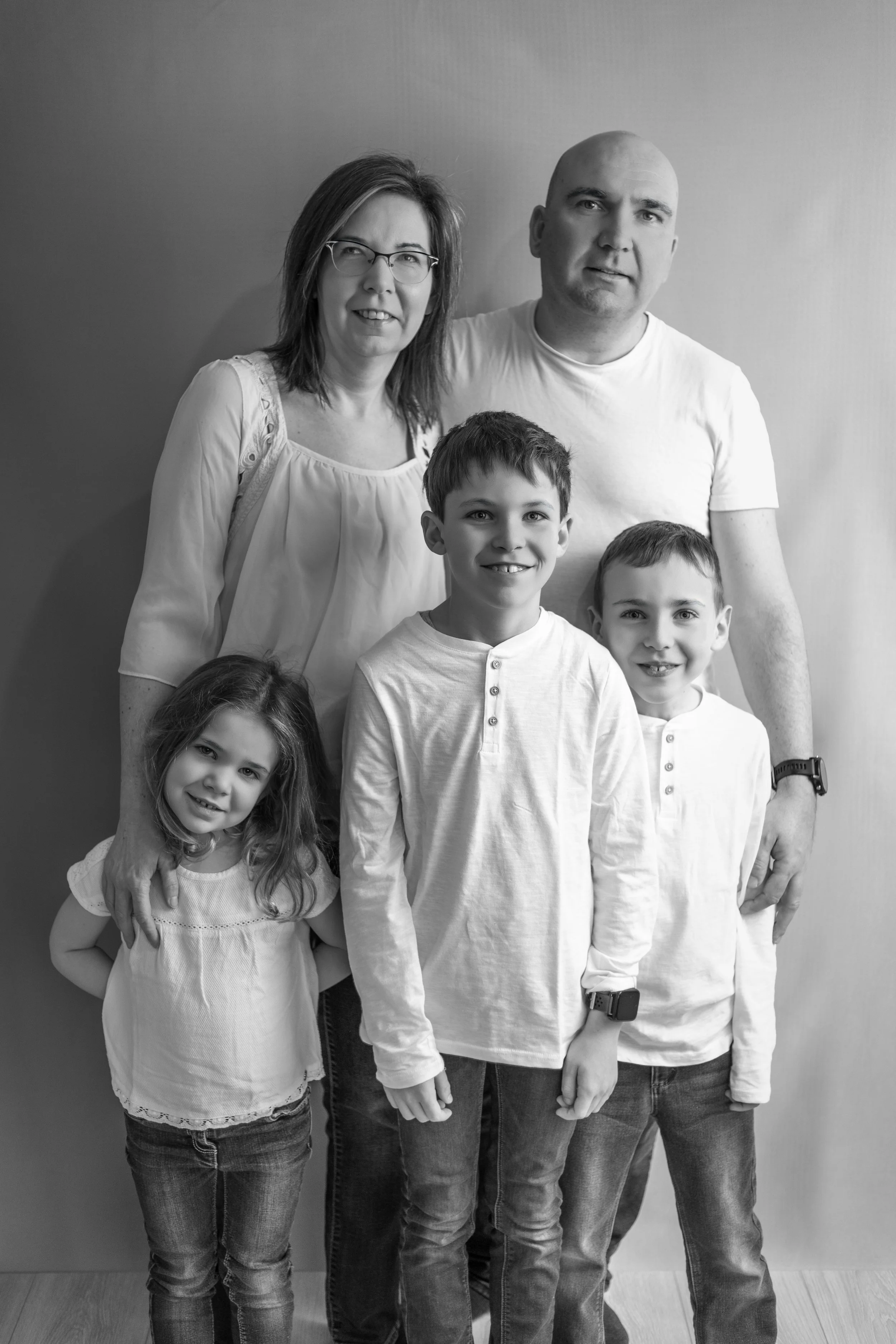 Photo de famille en noir et blanc avec deux adultes et trois enfants, tous souriants.