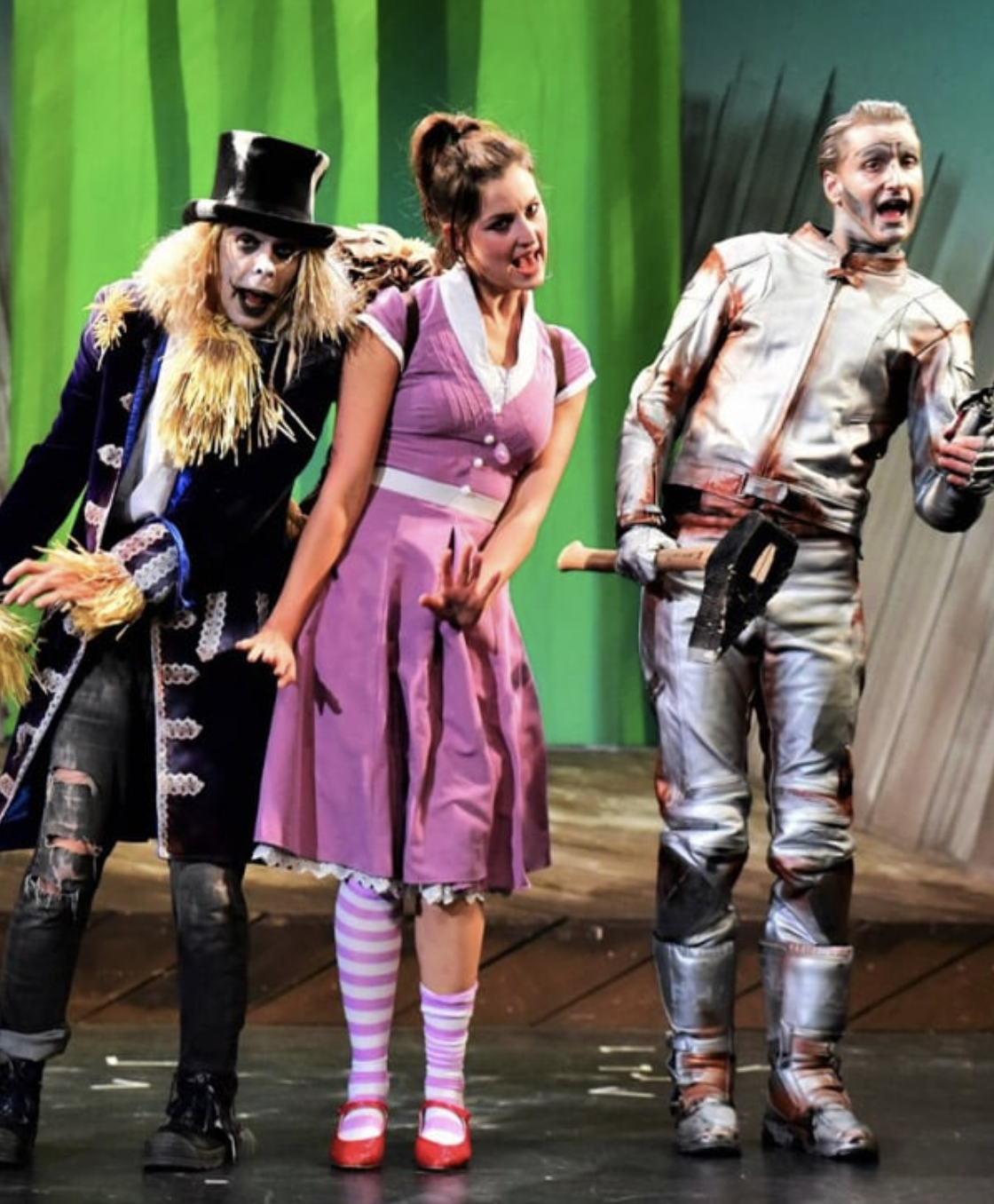 Menschen in bunten Kostümen auf einer Bühne im Theaterstück.