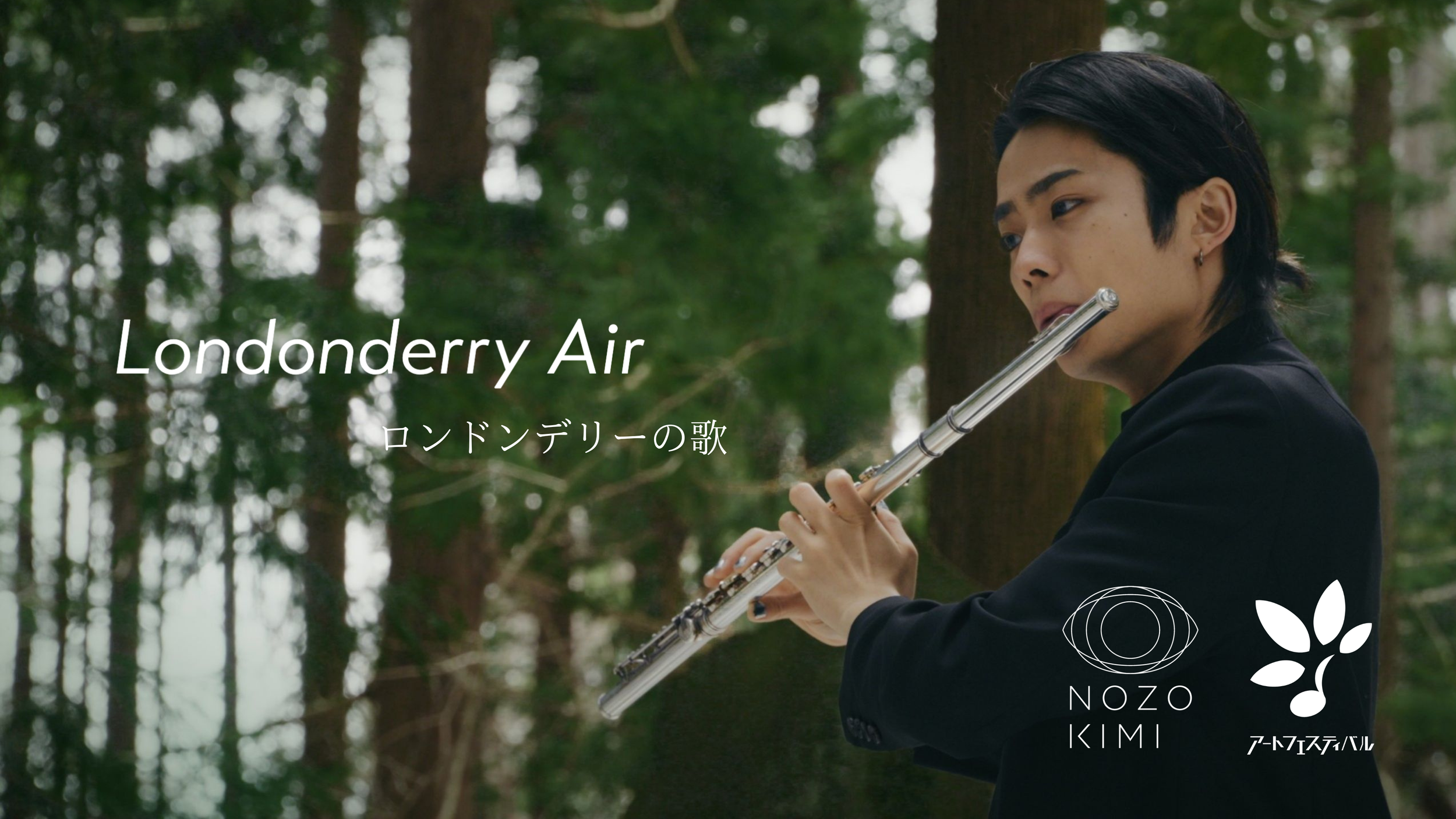 林の中でフルートを演奏する若い男性の写真。