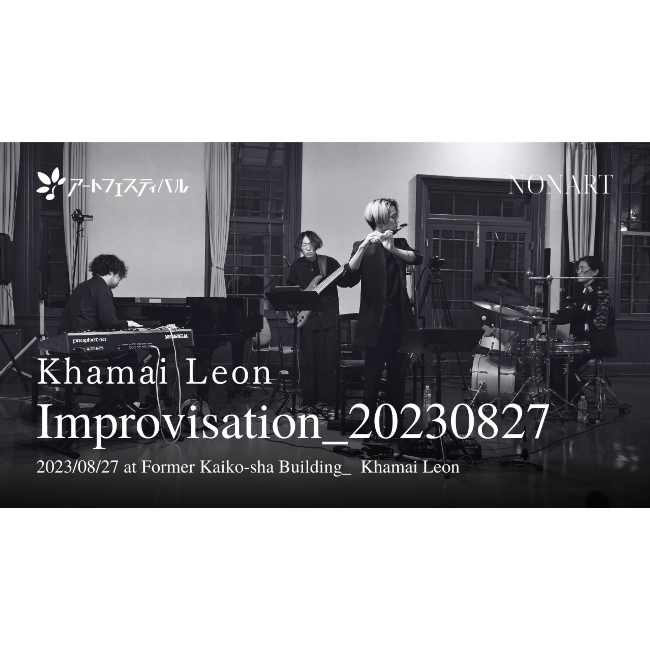 コンサートの舞台で演奏する4人のミュージシャンの写真。黒と白の写真で、中央のバイオリン奏者が注目されている。左側にピアノとキーボード、右側にドラムセット、その背後にギターとマイクスタンドが見える。