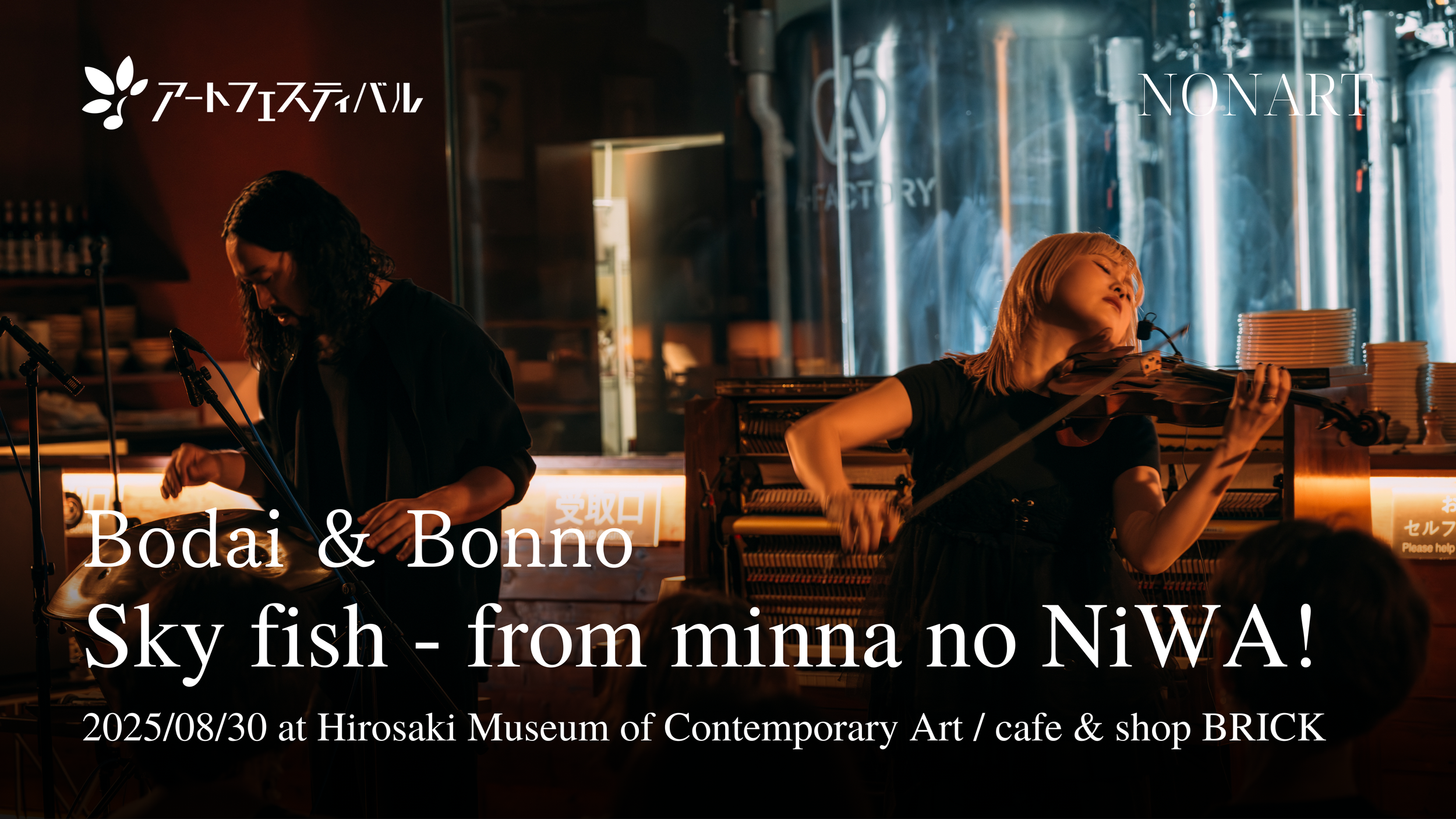 コンサートの写真。左側に男性のミュージシャン、右側に女性のバイオリニストが演奏している。背景は暖色系の照明と工業風の内装。