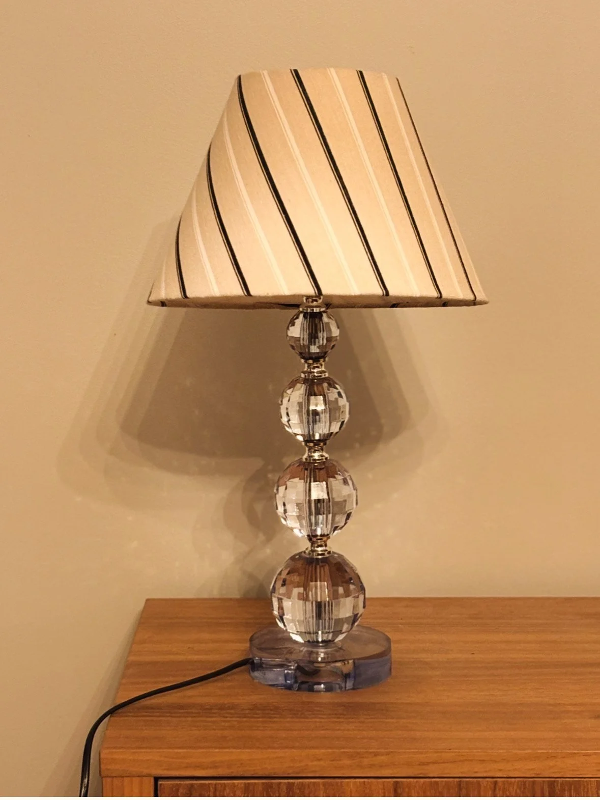 Table lamp with a fabric shade featuring diagonal black and white stripes, placed on a wooden surface against a plain wall.