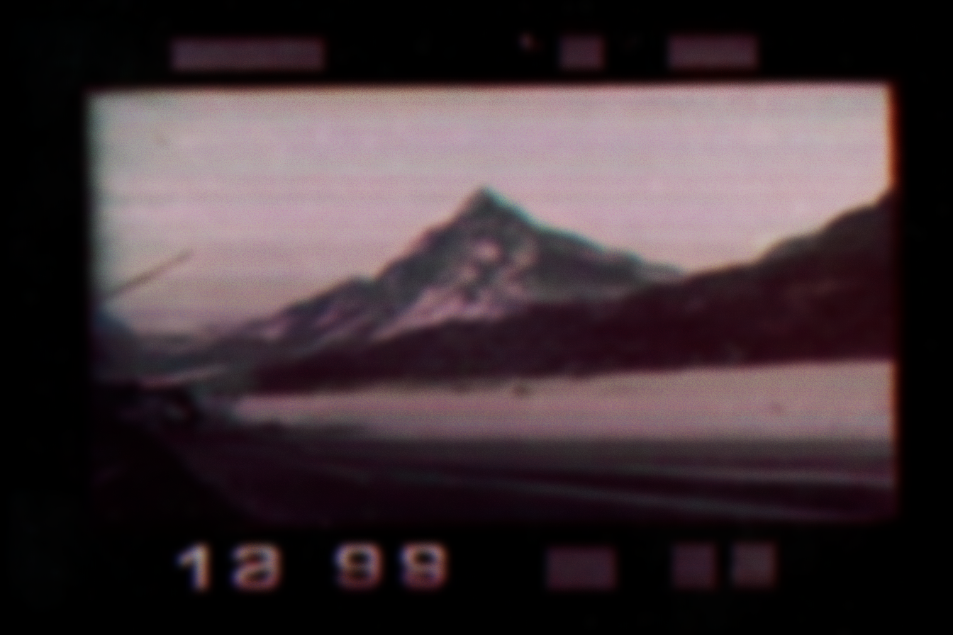 Blurred photograph of a mountain with a purple sky, possibly at dawn or dusk, with digital timestamp reading "12 93" at the bottom.