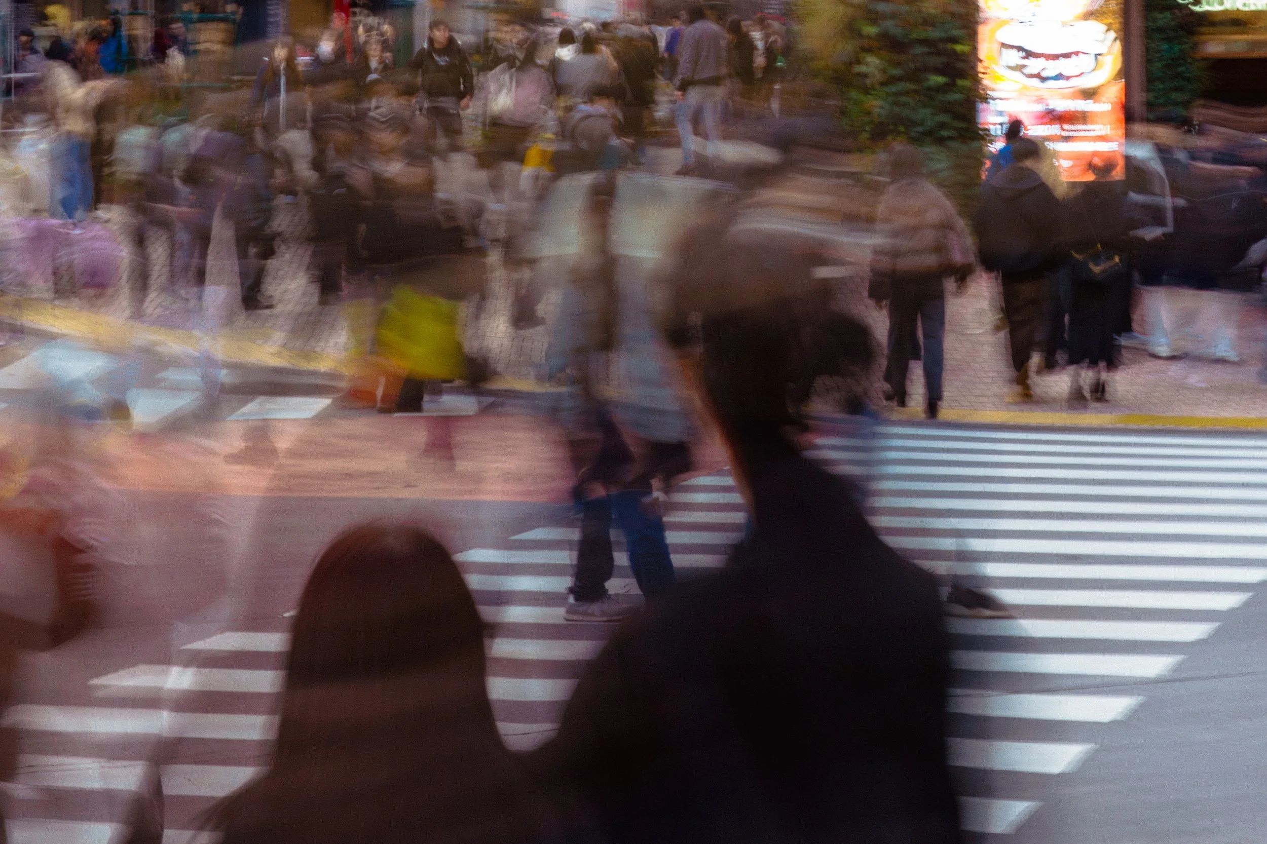 A busy city crosswalk with people walking in various directions, city street scene with a blurred motion effect