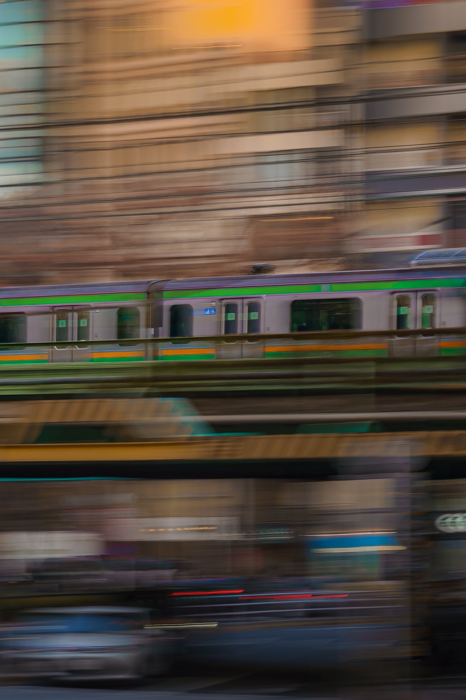 Blurred motion of a train traveling in an urban area with buildings in the background.