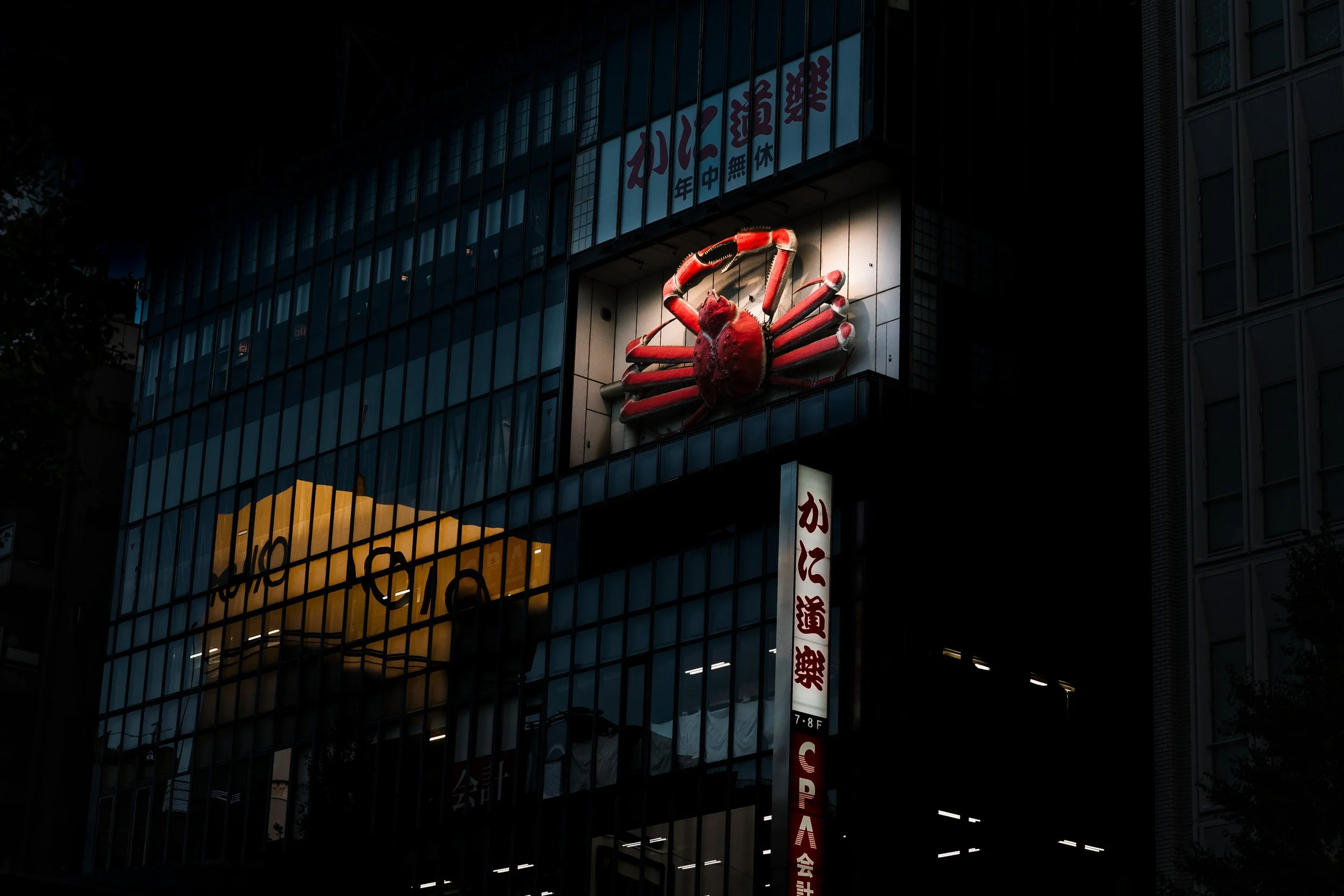 Nighttime city building with illuminated crab sign on the exterior
