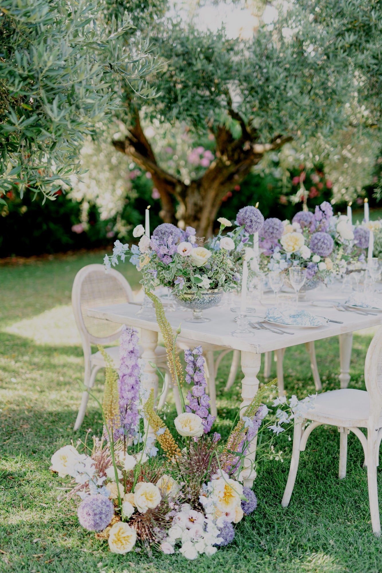 Decorative outdoor table setting with floral arrangements and chairs in a garden
