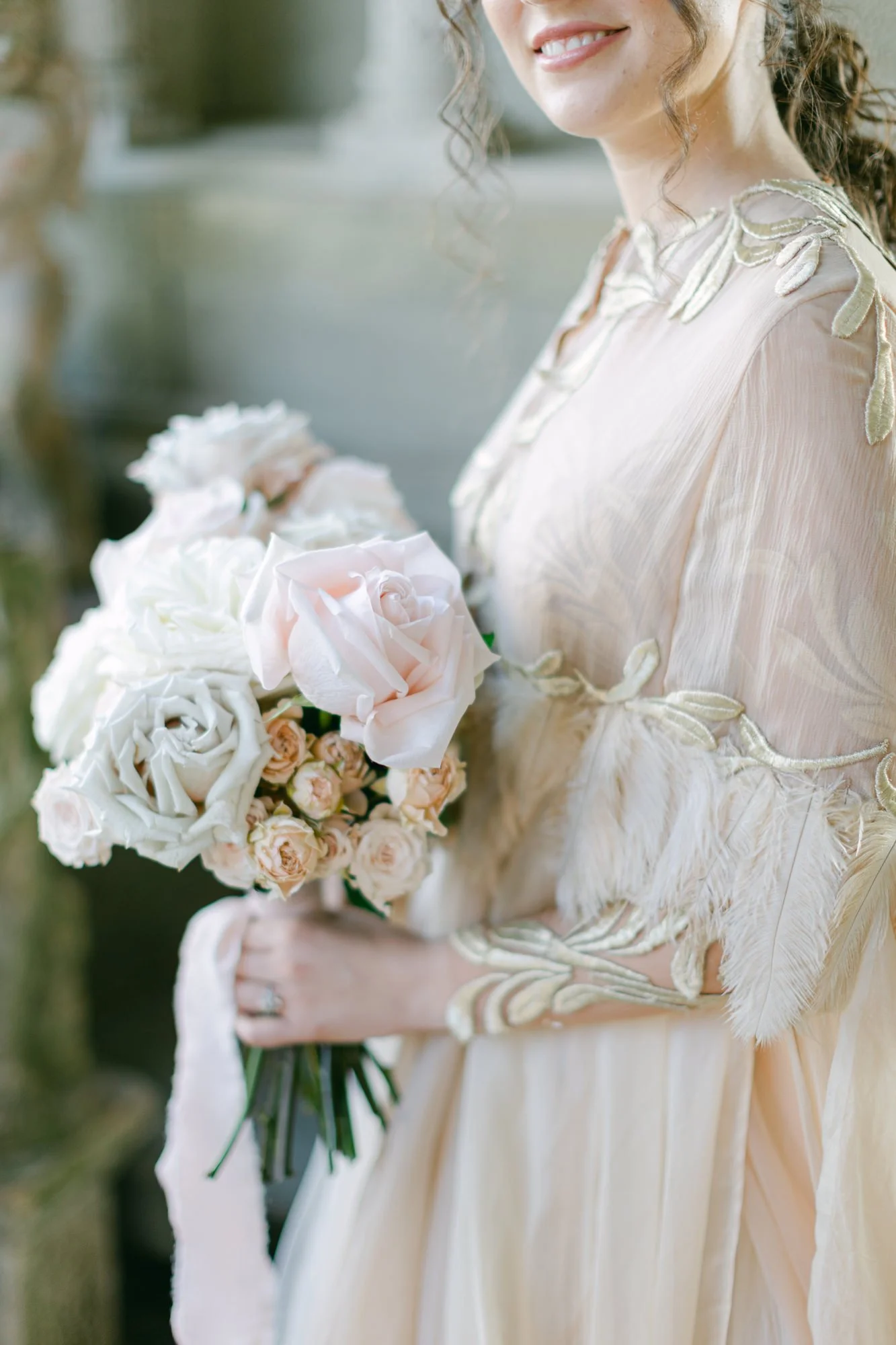A woman in a light-colored dress holding a bouquet of pink and white roses.