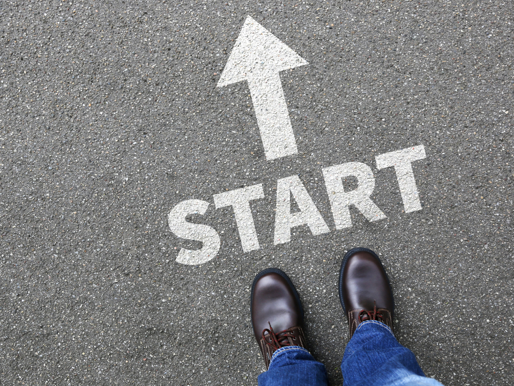 Boden mit Startlinie und Pfeil markiert, Person in Stiefeln steht vor der Linie