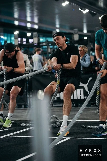 Mannen die deelnemen aan een krachttraining met touwen in een sportschool.