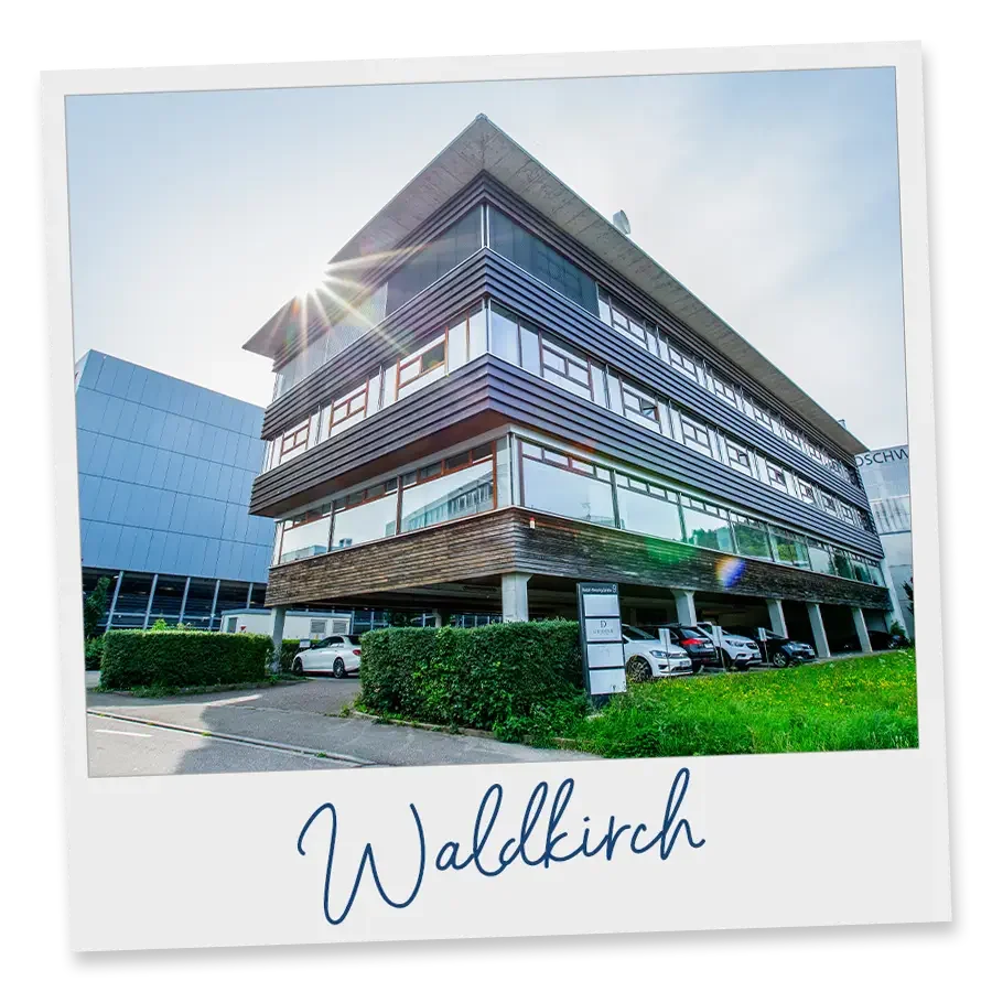 Moderne mehrstöckige Bürogebäude in Waldkirch, Deutschland, mit Parkplatz im Vordergrund, sonniger Himmel, Sonnenstrahlen
