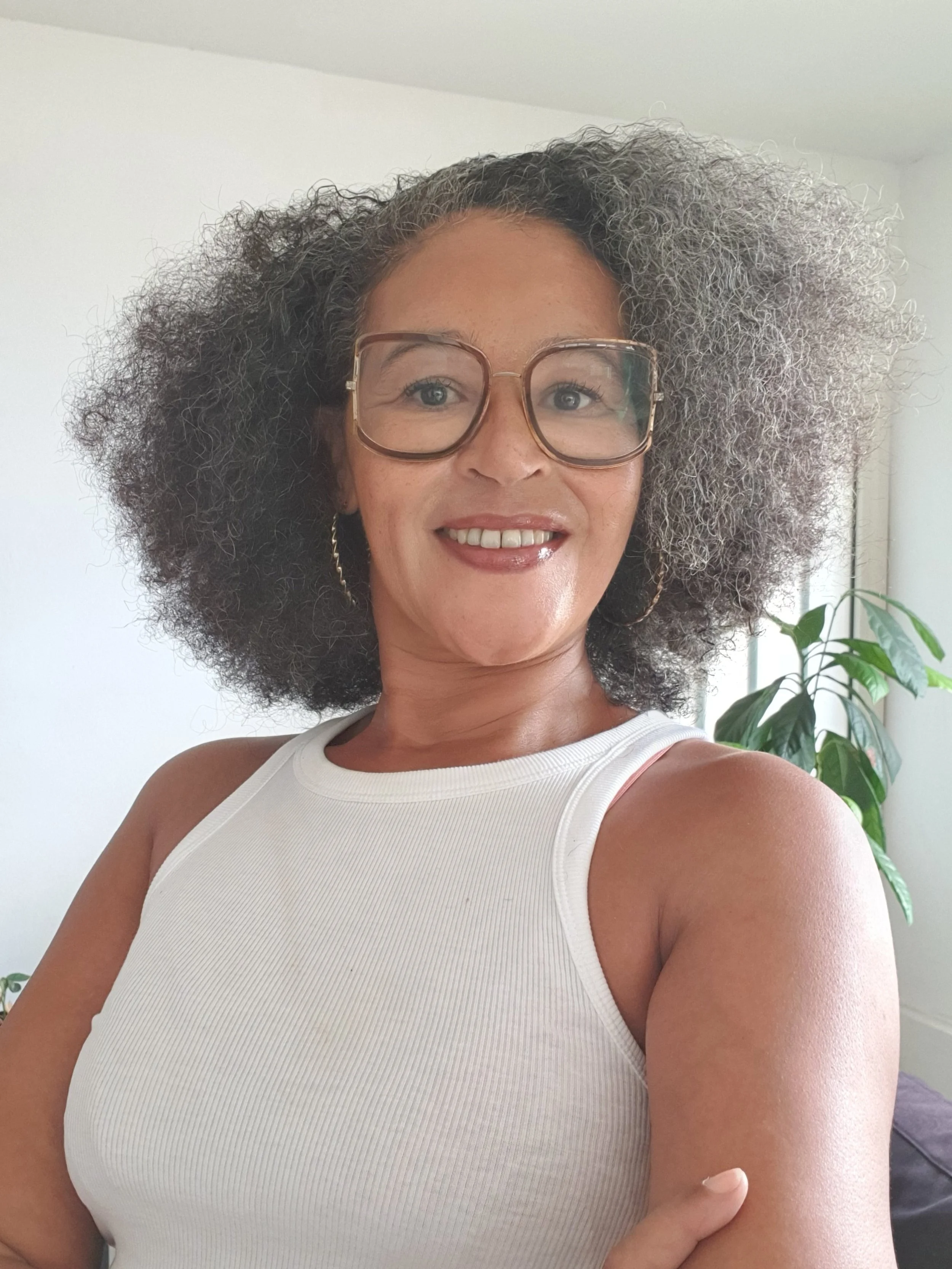 Une femme souriante et Confiante, avec un Flow Tangible portant des lunettes et un haut blanc, une belle Femme de 50 ans.