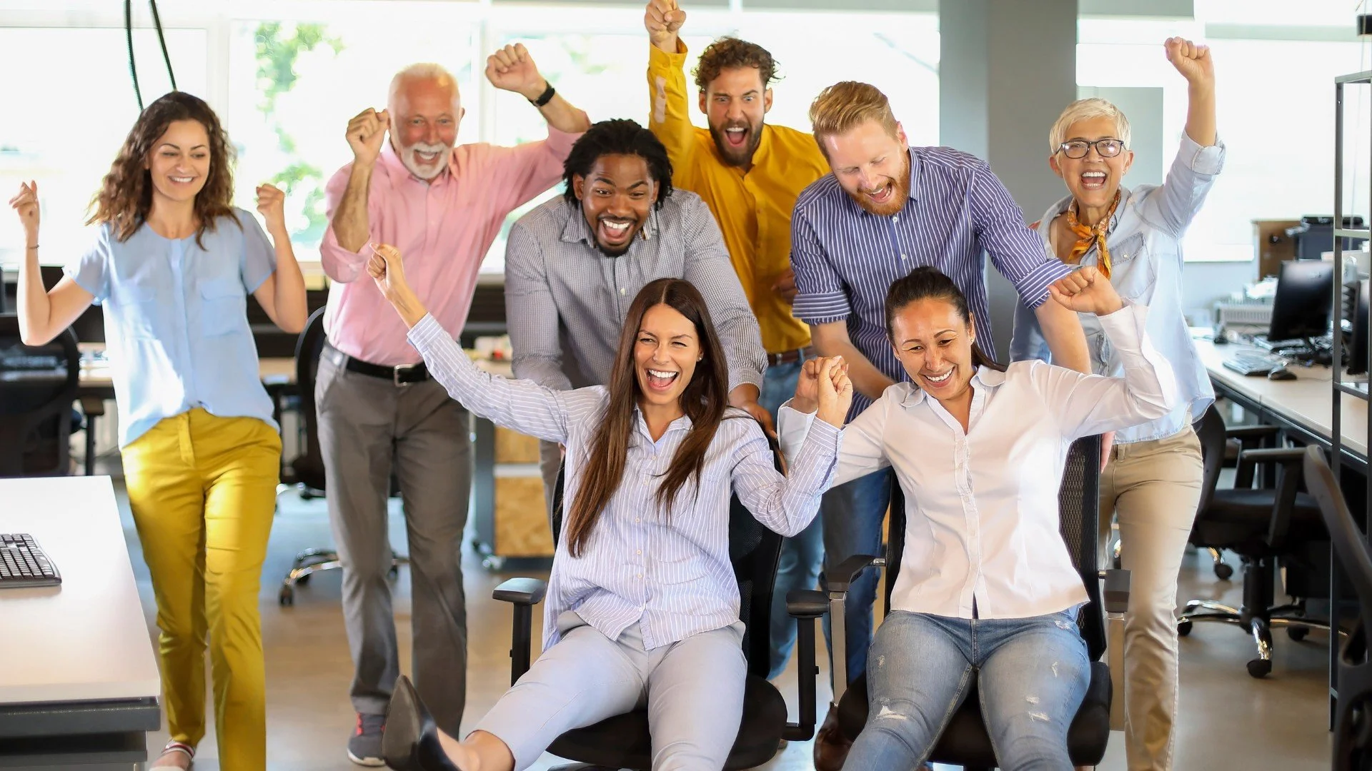 group of diverse coworkers celebrating and cheering in an office setting