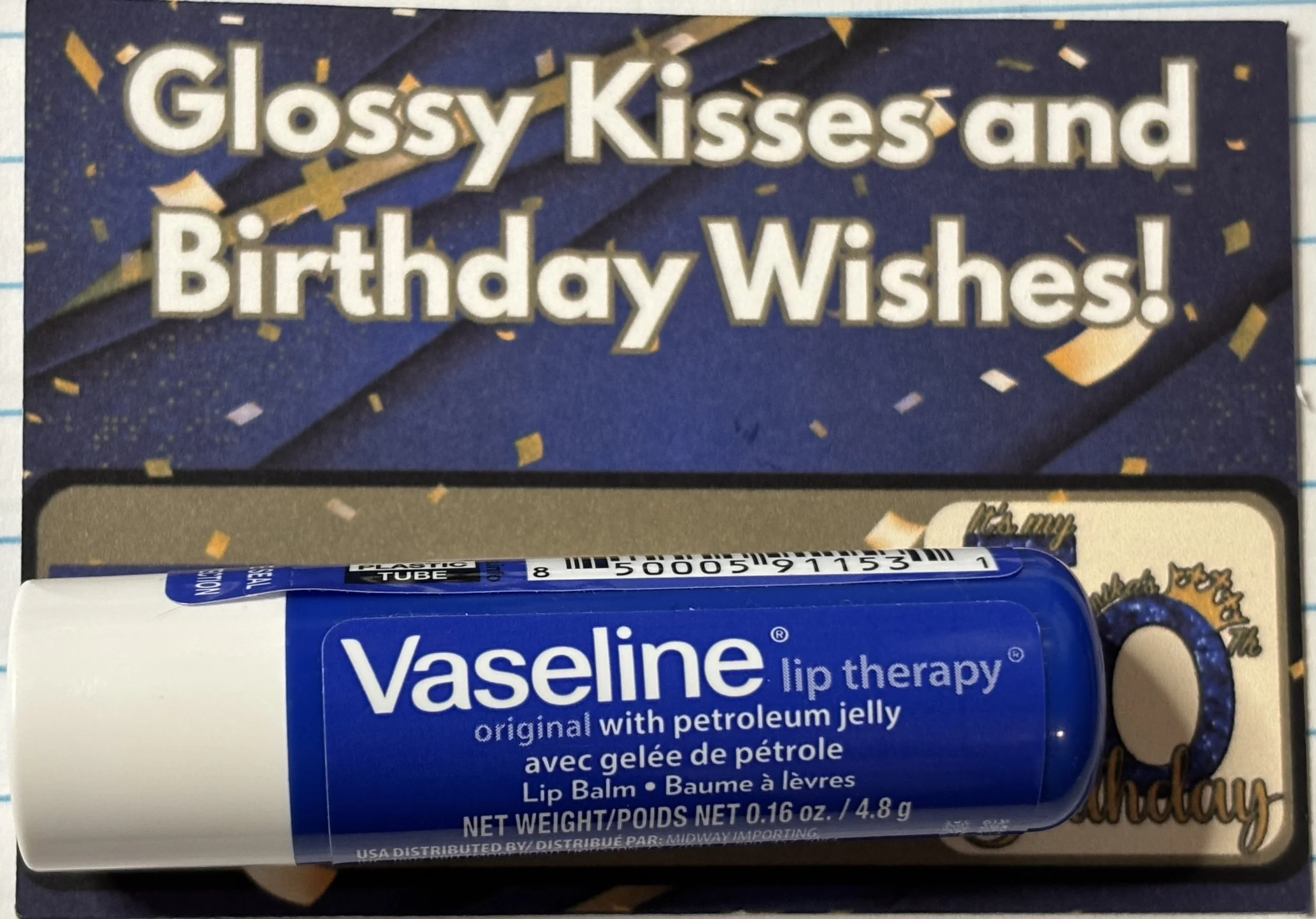 Vaseline lip therapy lip balm in original petroleum jelly flavor lying on a festive birthday card with blue, gold, and confetti design.