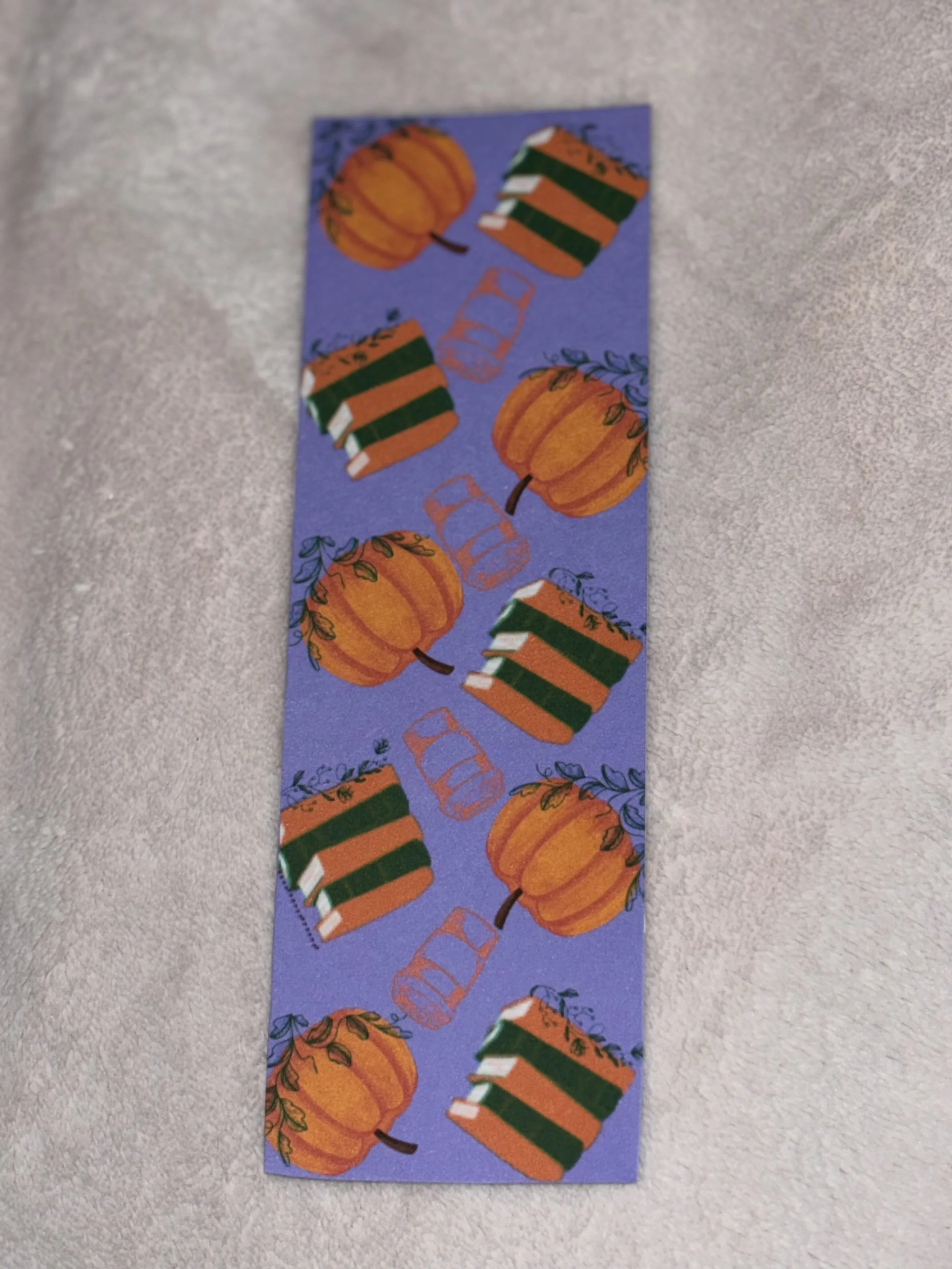 A purple Thanksgiving-themed decorative strip with pumpkins, colorful books, and glasses.