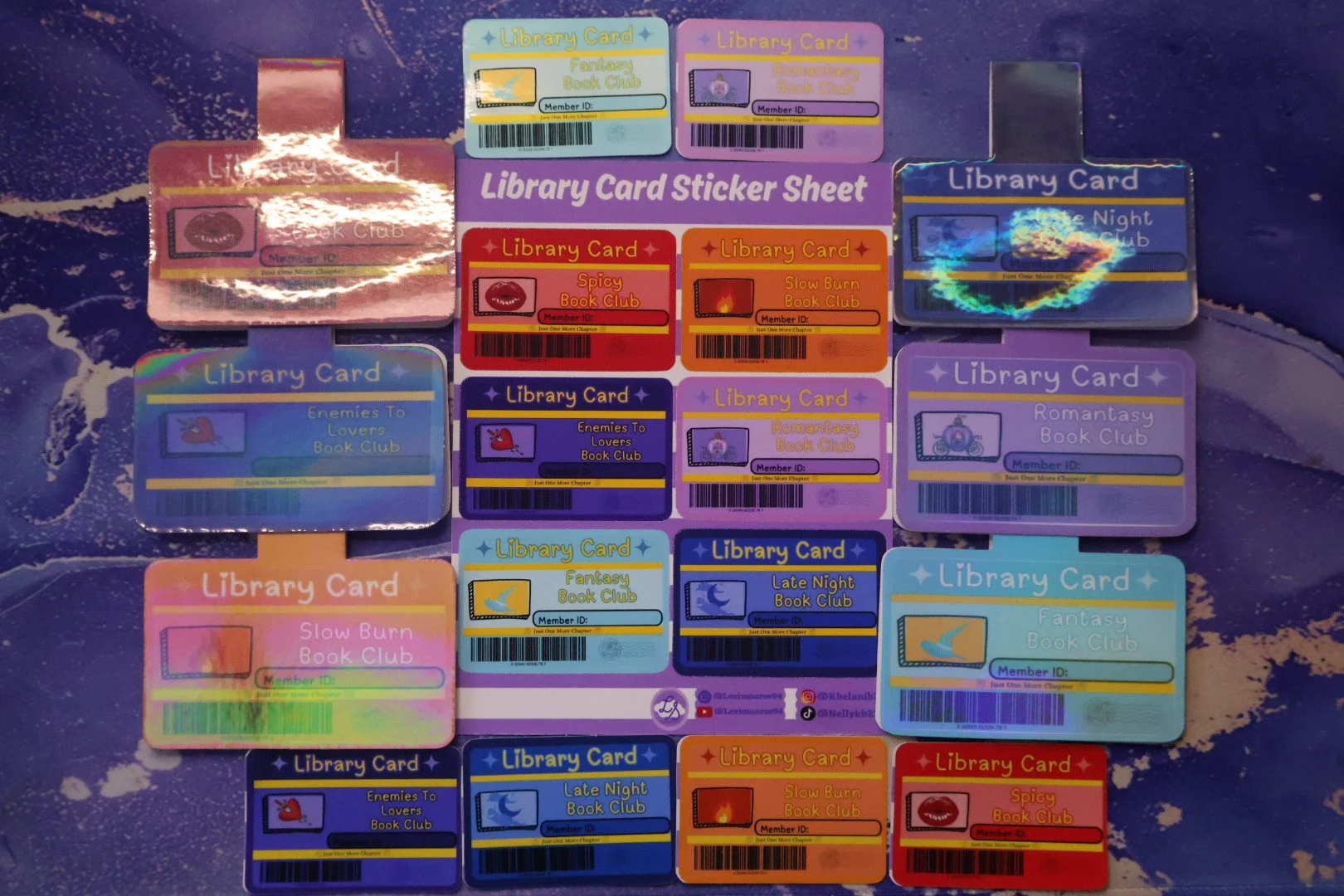Collection of colorful library card stickers with different themes and designs placed on a blue surface with white and purple patterns.