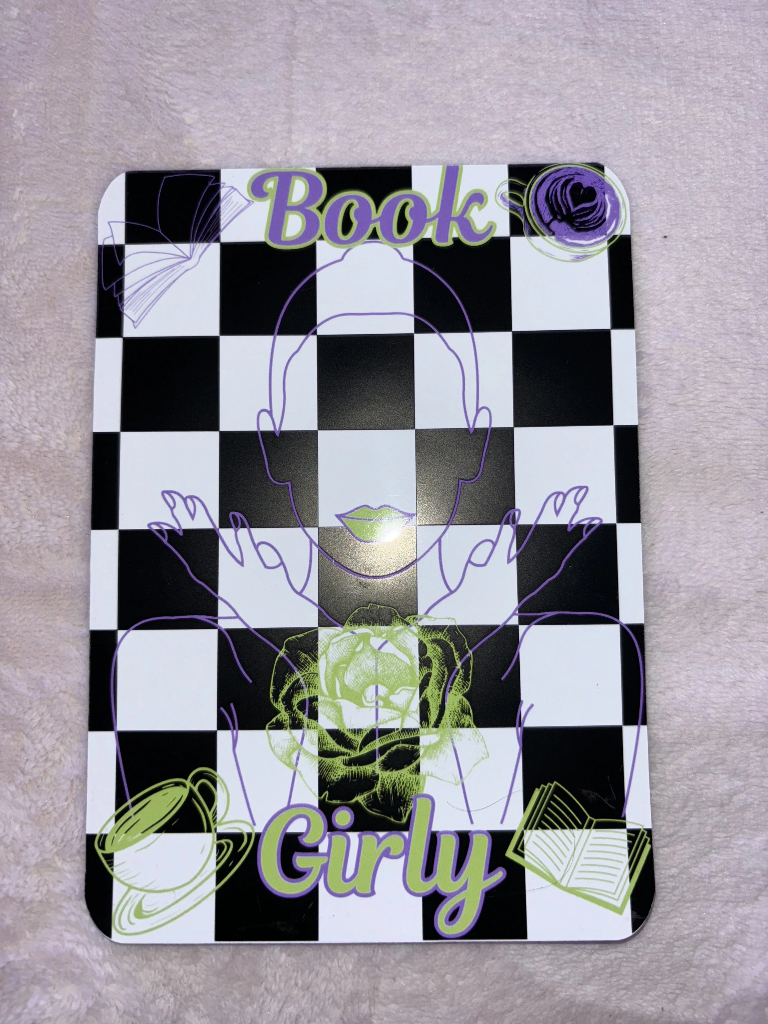 A decorative black and white checkered book cover with colorful outline drawings of a woman's face, hands, a coffee cup, a rose, and an open book. The words 'Book Girl' are written at the top and bottom in purple and green text.