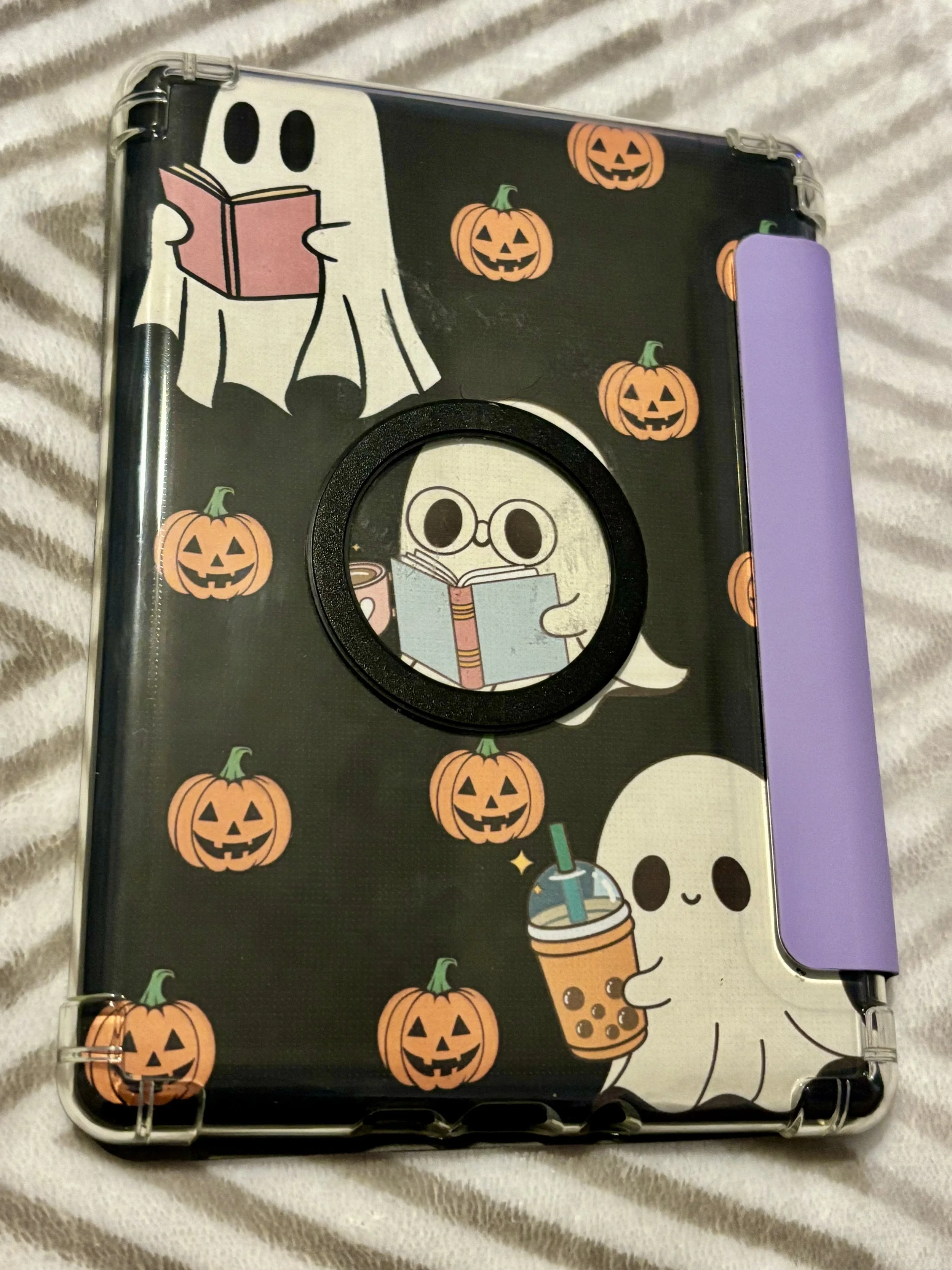 A tablet case with Halloween-themed cartoon ghost and pumpkin characters, some holding drinks, set against a dark background.