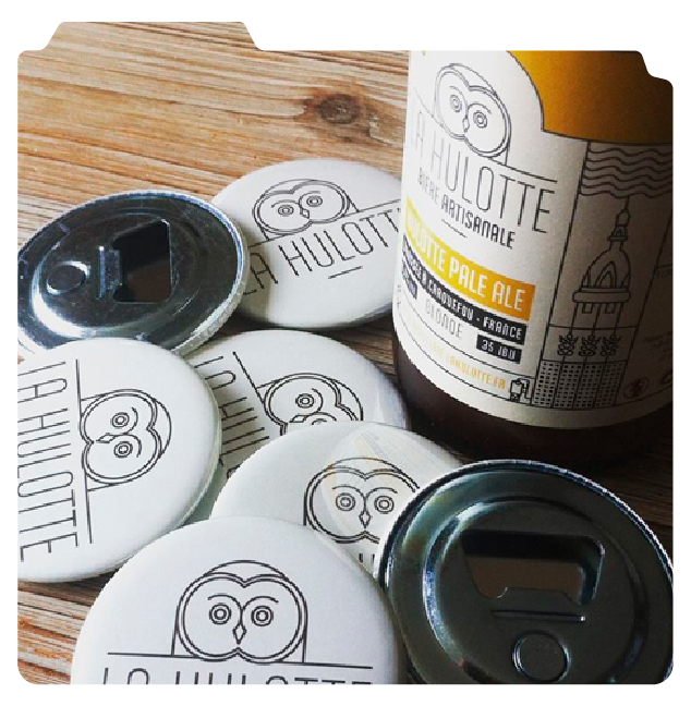 Etiquette de bière artisanale La HULOTTE, bière blonde, avec décapsuleurs sur une table en bois.