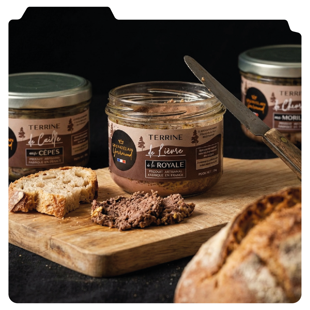 Graphisme de packaging et identité de marque du Châtelain Gourmand, produits d'épicerie fine : ici Pot de terrine sur une planche en bois, entouré de pain et de deux autres pots de terrine, avec un couteau à côté.