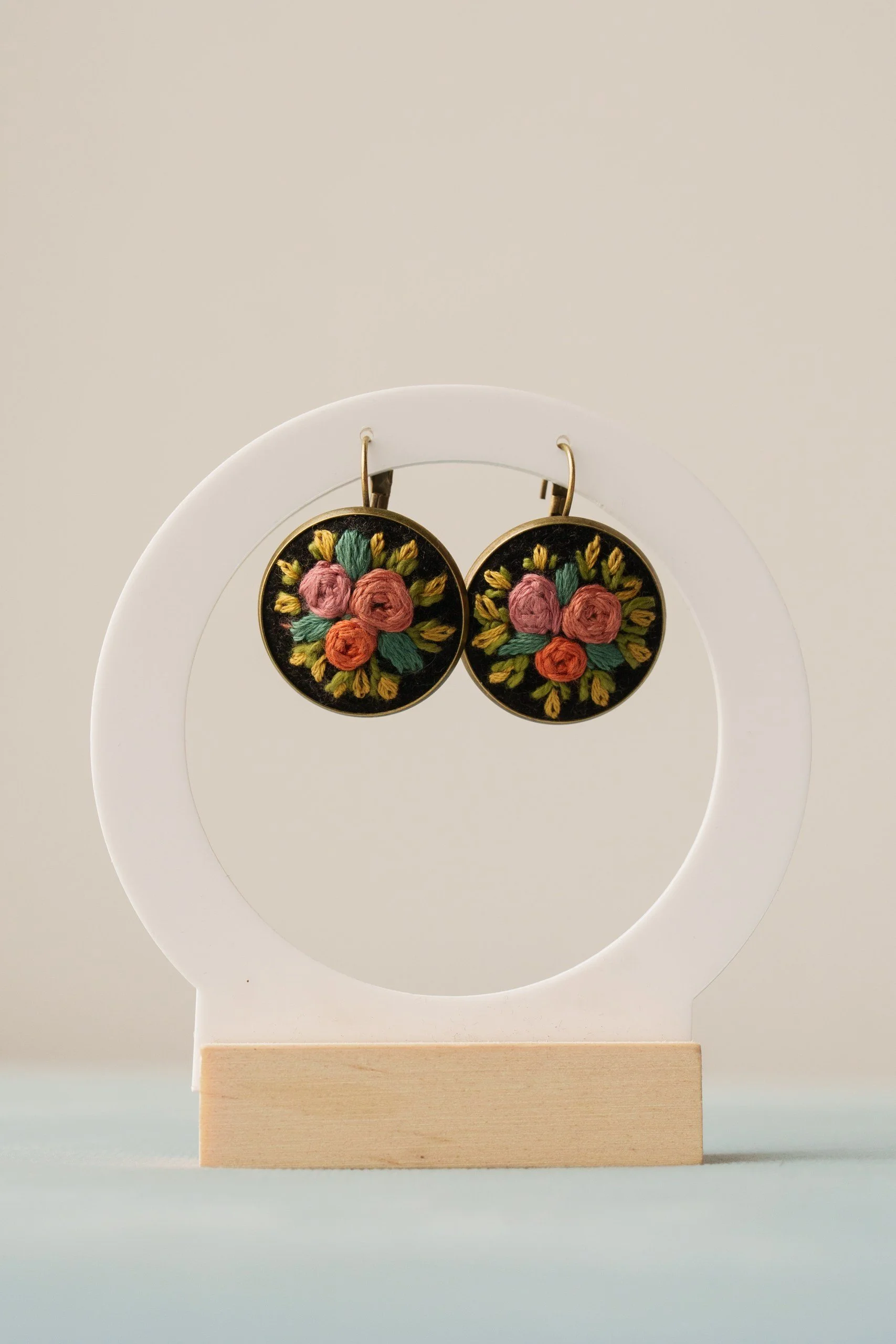 Embroidery floral earrings hanging on a display stand