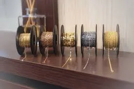 Six spools of glittery thread in different colors on a wooden surface