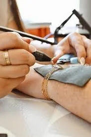 A person receiving a medical or cosmetic procedure on their arm, with another individual performing the procedure using a device, in a clinical setting.