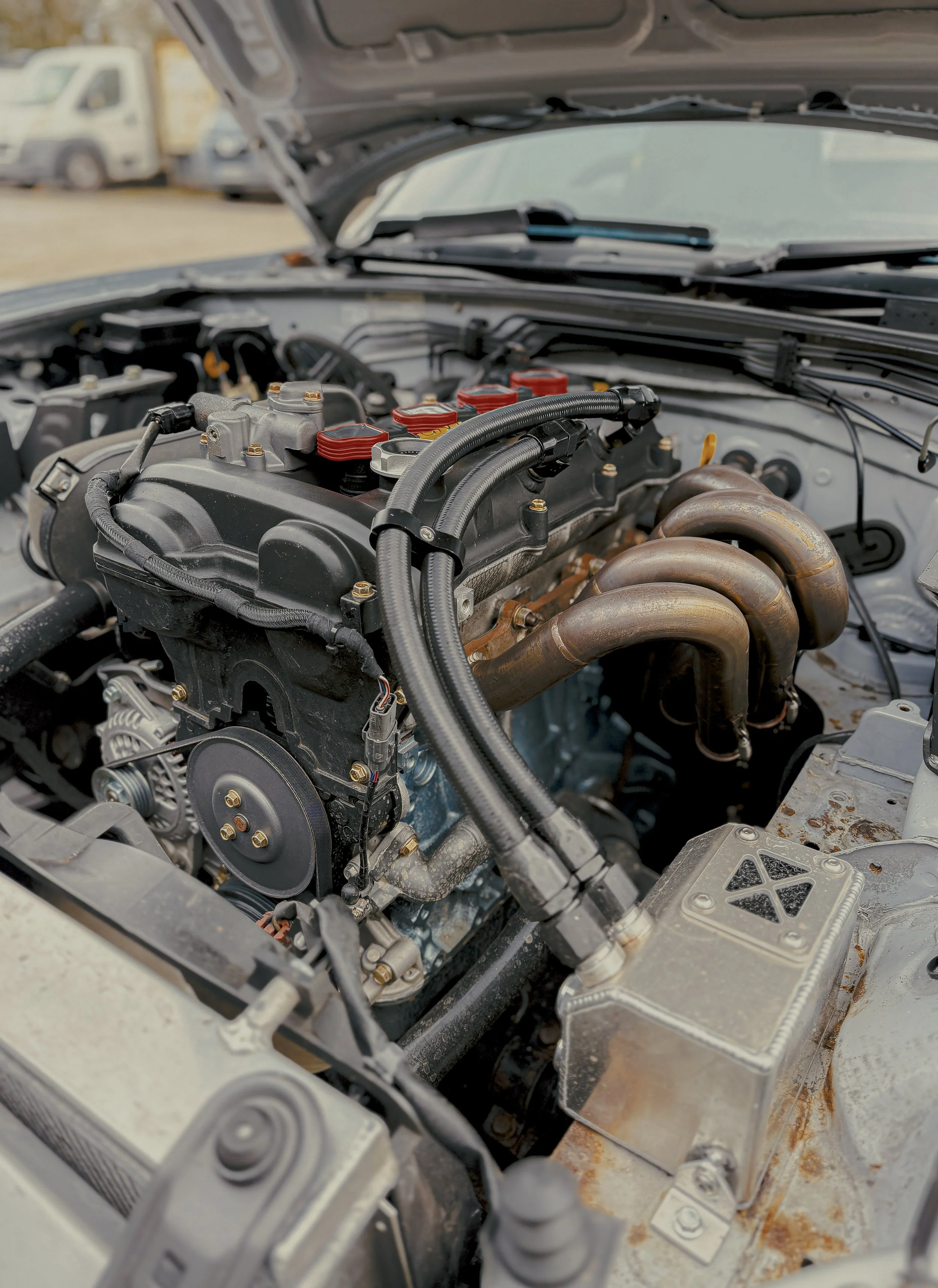 Close-up of a car engine with visible exhaust manifold and various engine components. Mazda Miata mk2 NBFL Engine Eunos 