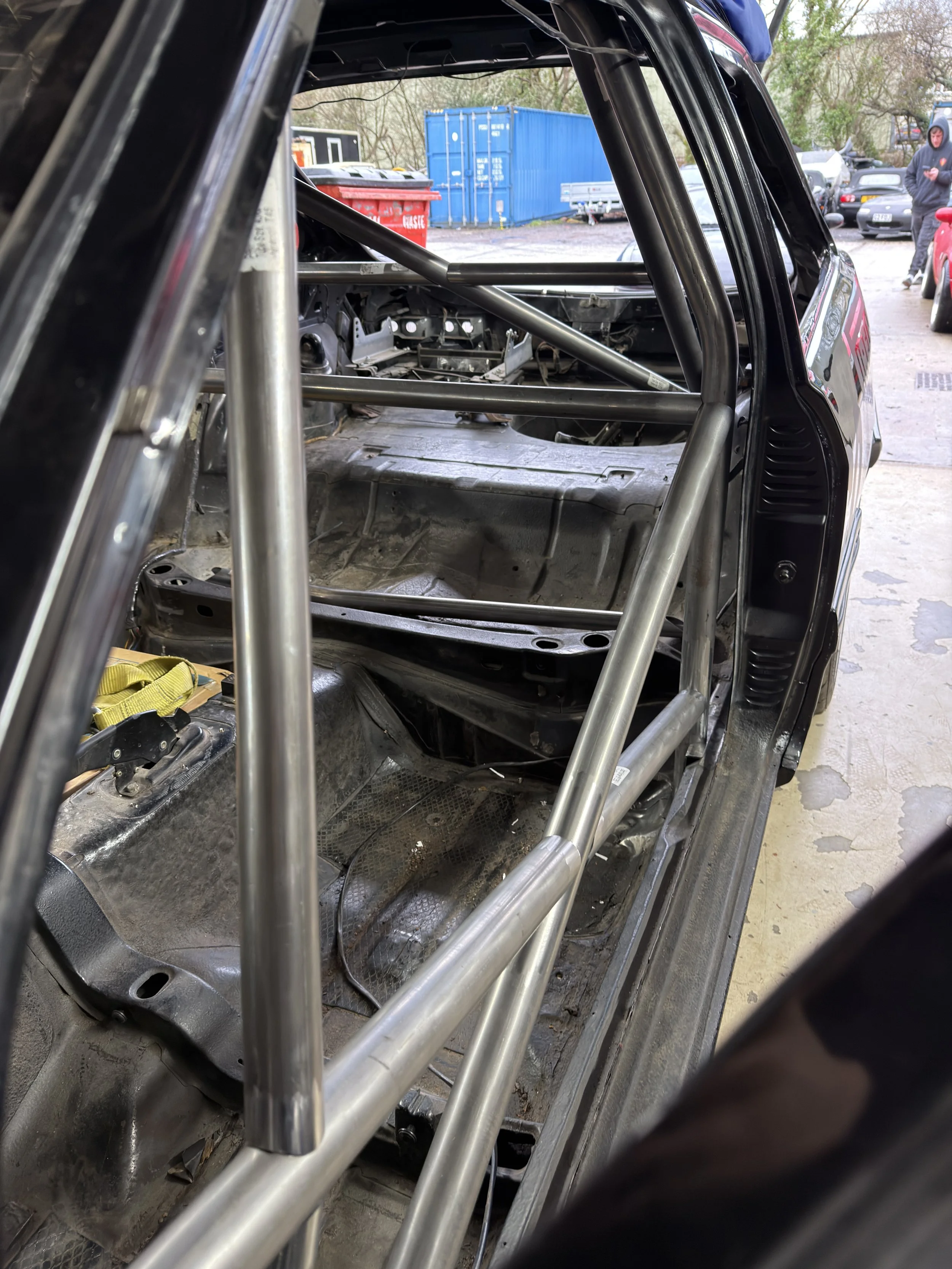 Inside a race car with a custom roll cage, showing the empty interior with exposed metal framework and no seats. FORD SEIRRA ROLL CAGE