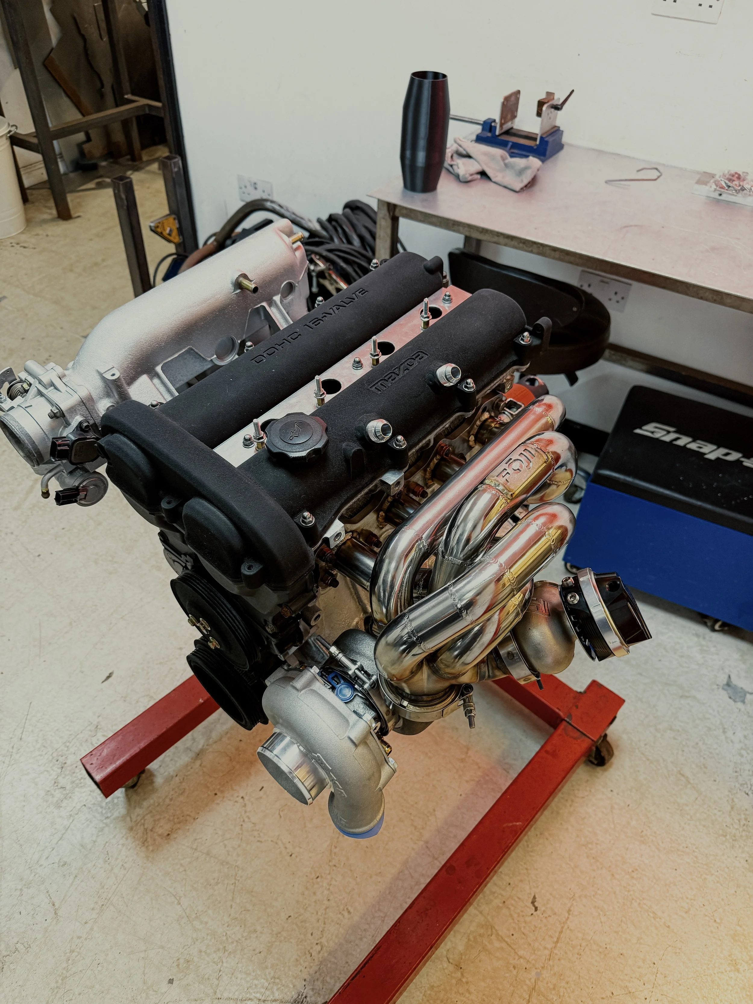 A car engine on a red engine stand in a workshop Mazda Miata MX5 MK1 Eunos 1.6 