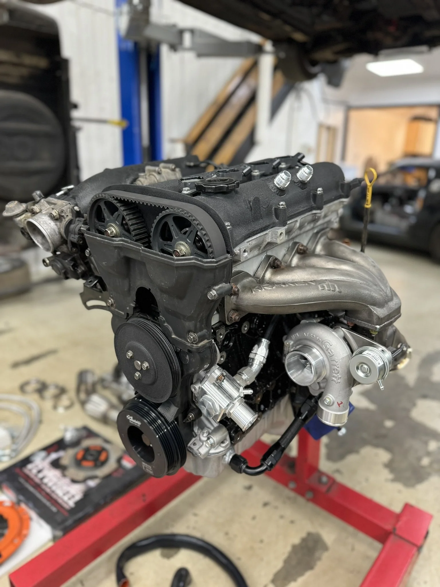 1.6 Mazda Miata Mx5 Eunos Engine Automotive engine installed on a red engine stand in a garage workshop.